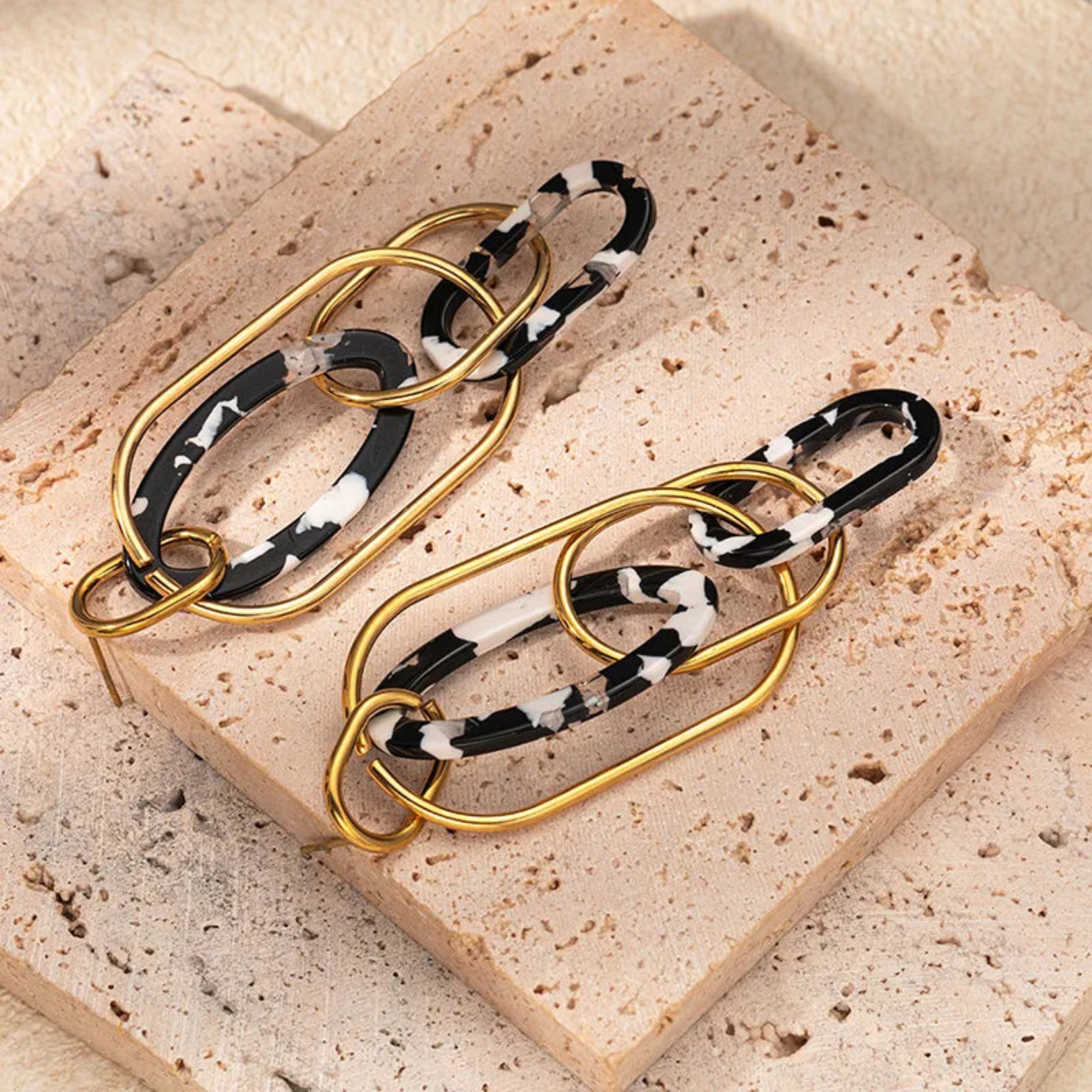 Bracelets with gold and black patterned bands on a textured beige surface