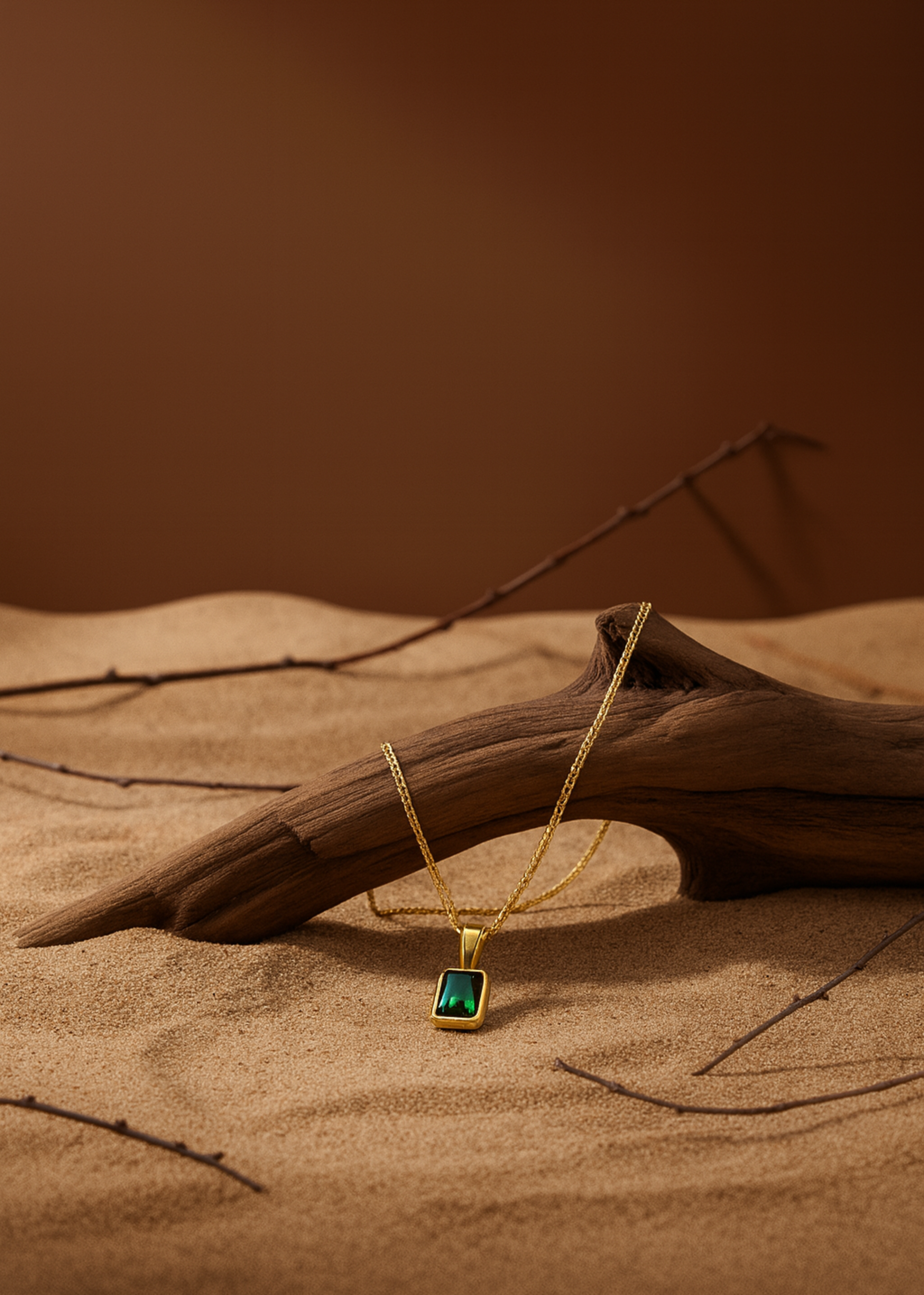 Gold necklace with a green gemstone pendant on a brown background