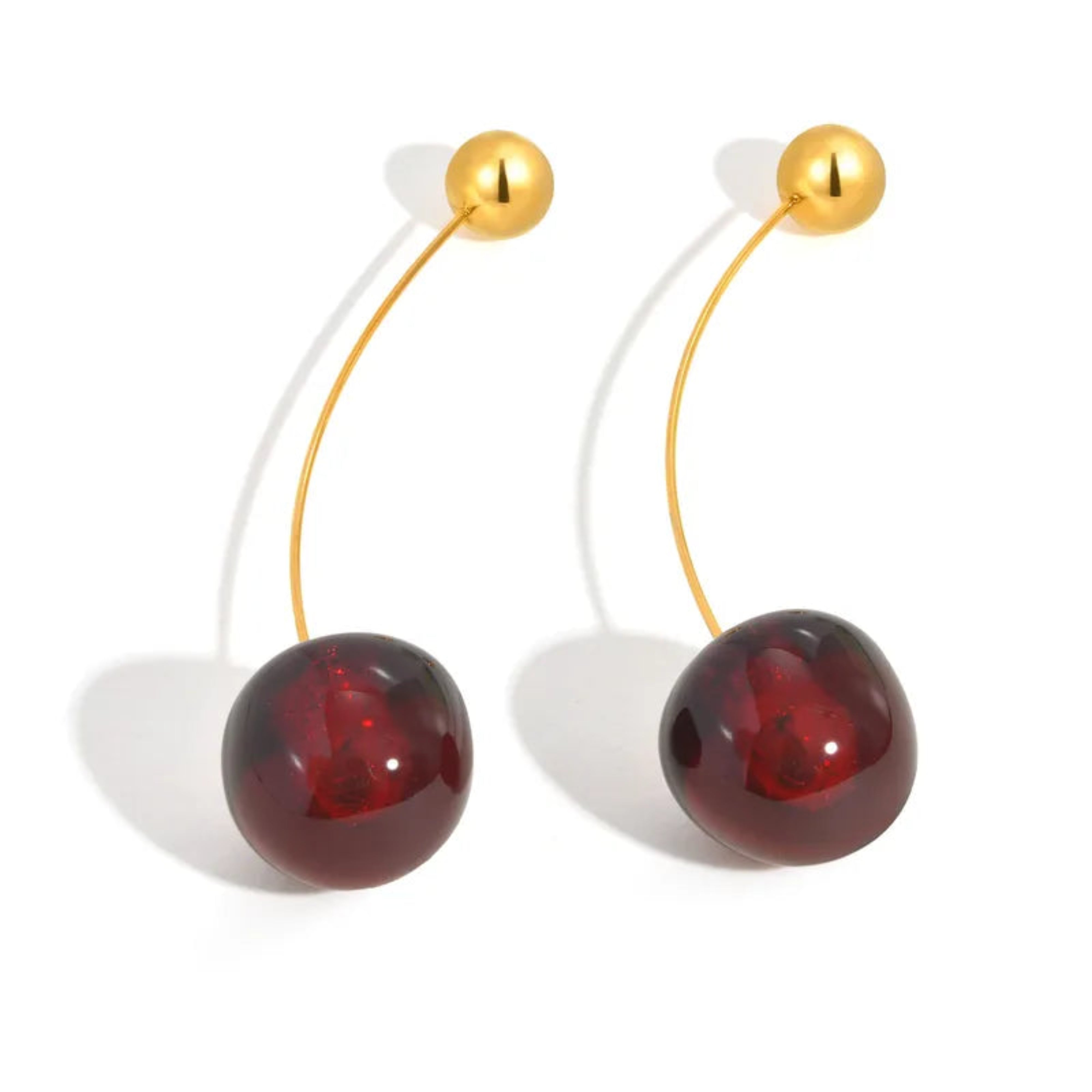 Cherry-shaped earrings with red balls and gold stems on a white background