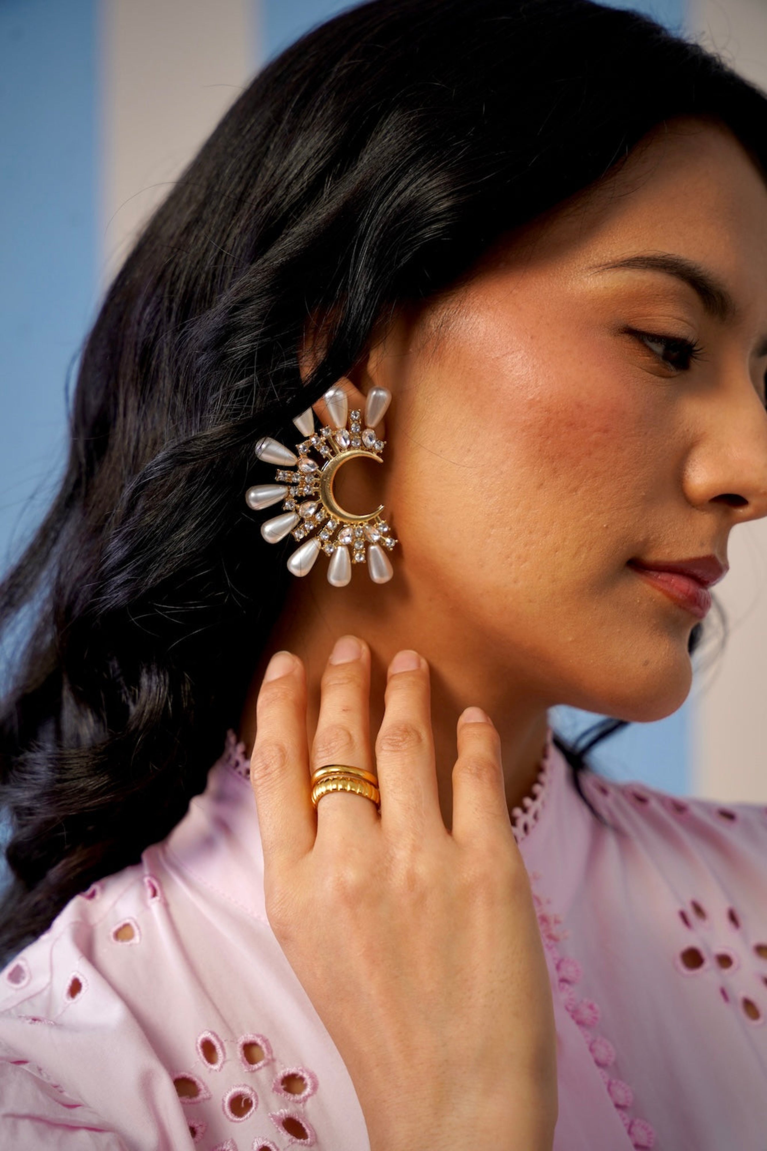 Woman wearing a gold earring and ring with a blurred background