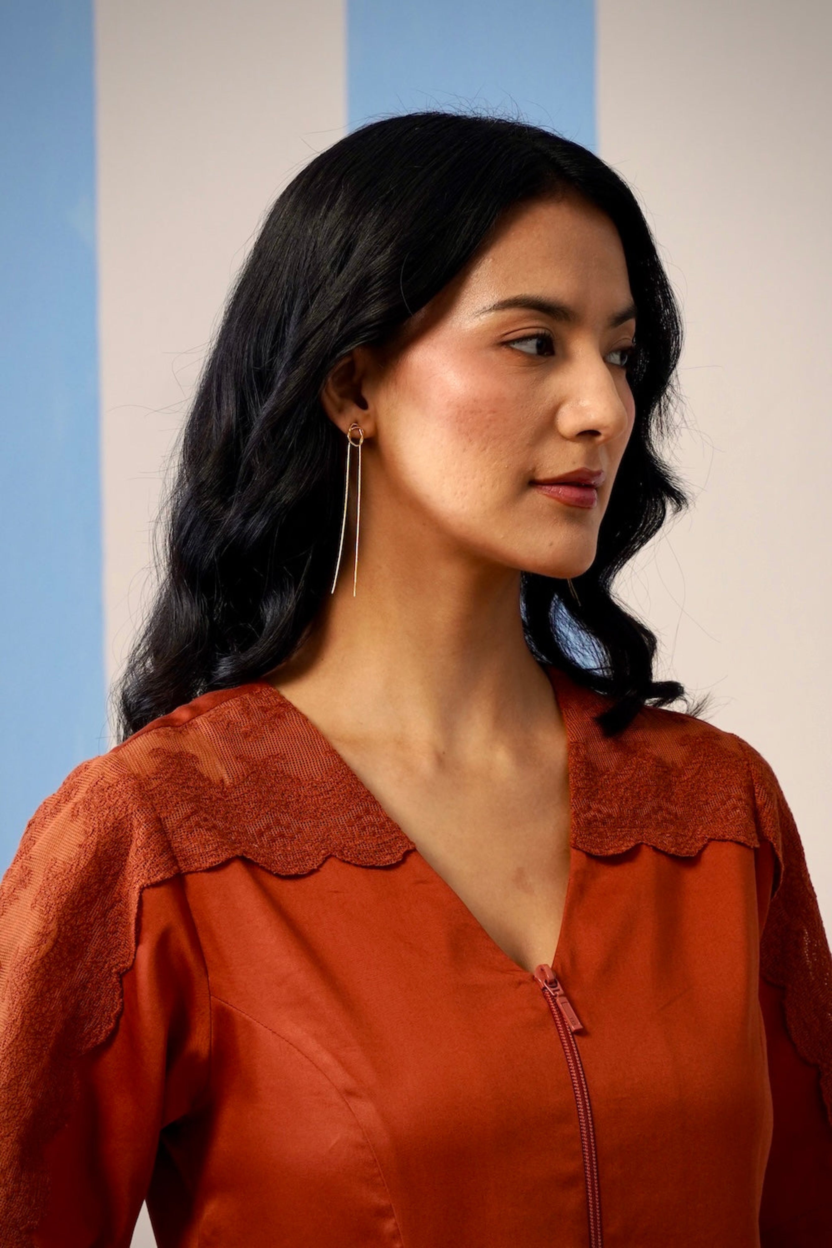 Woman wearing a rust-colored blouse with a plain background