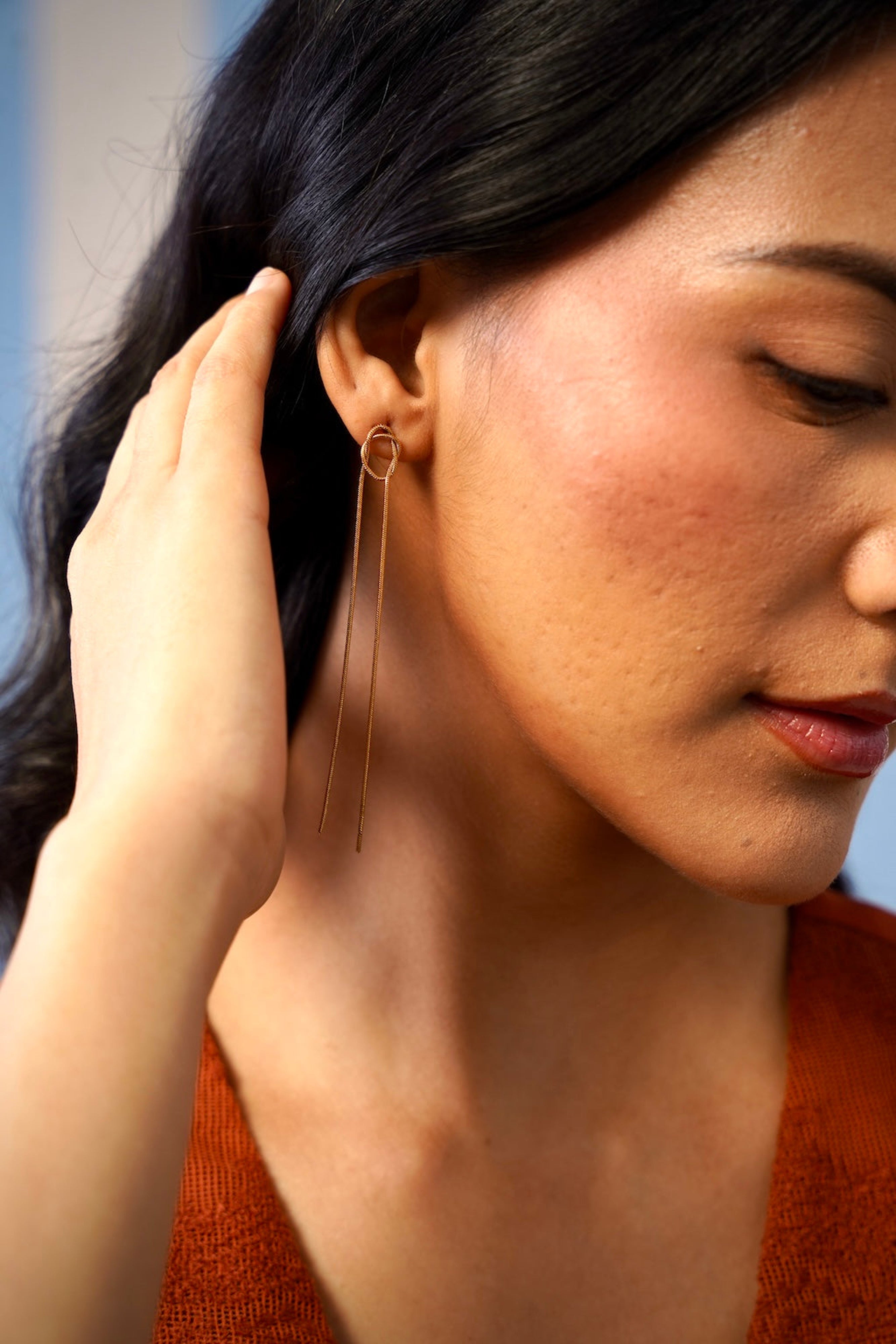 Close-up of a woman wearing a gold earring with a blurred background
