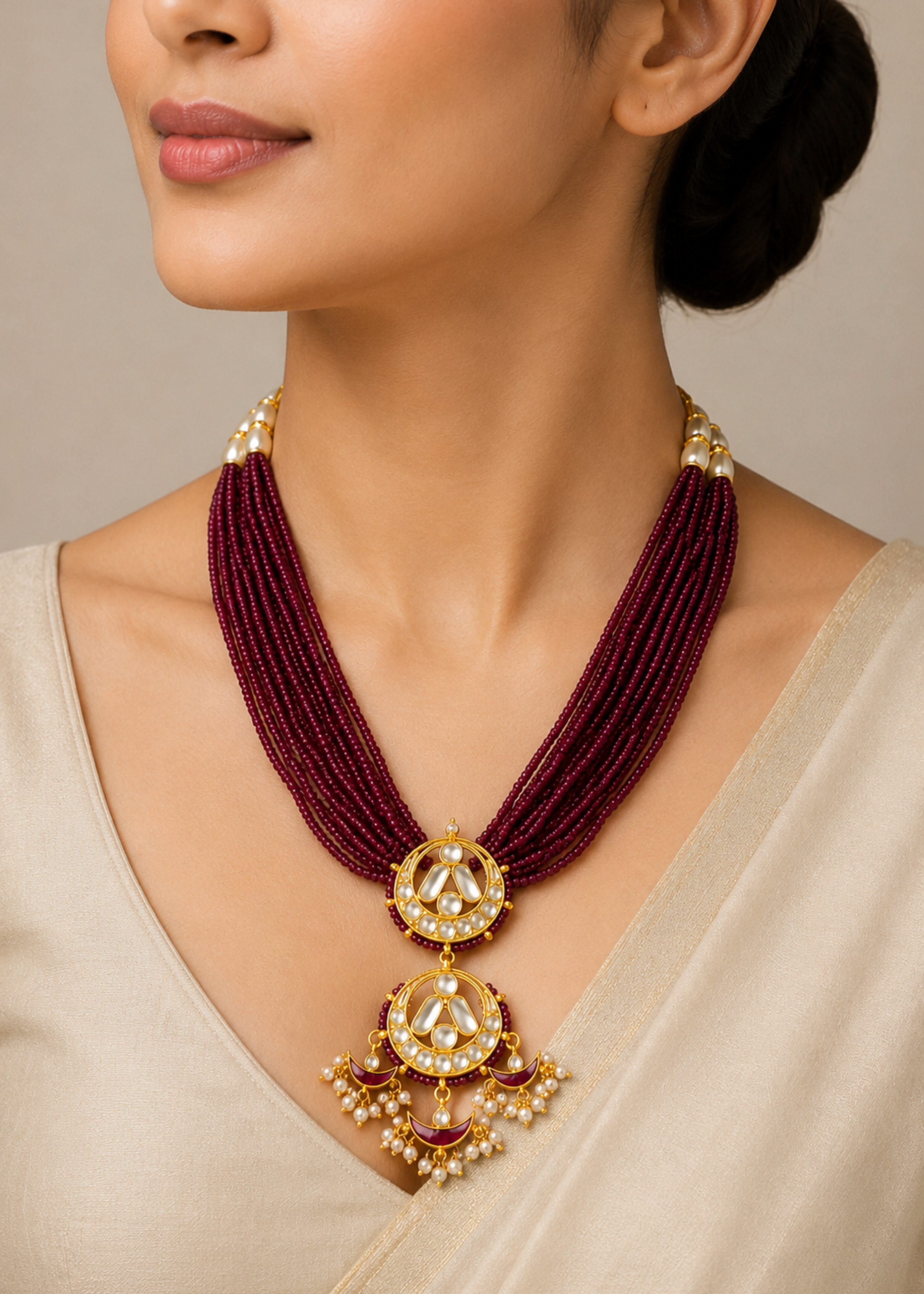 Woman wearing a maroon necklace with gold pendants on a neutral background