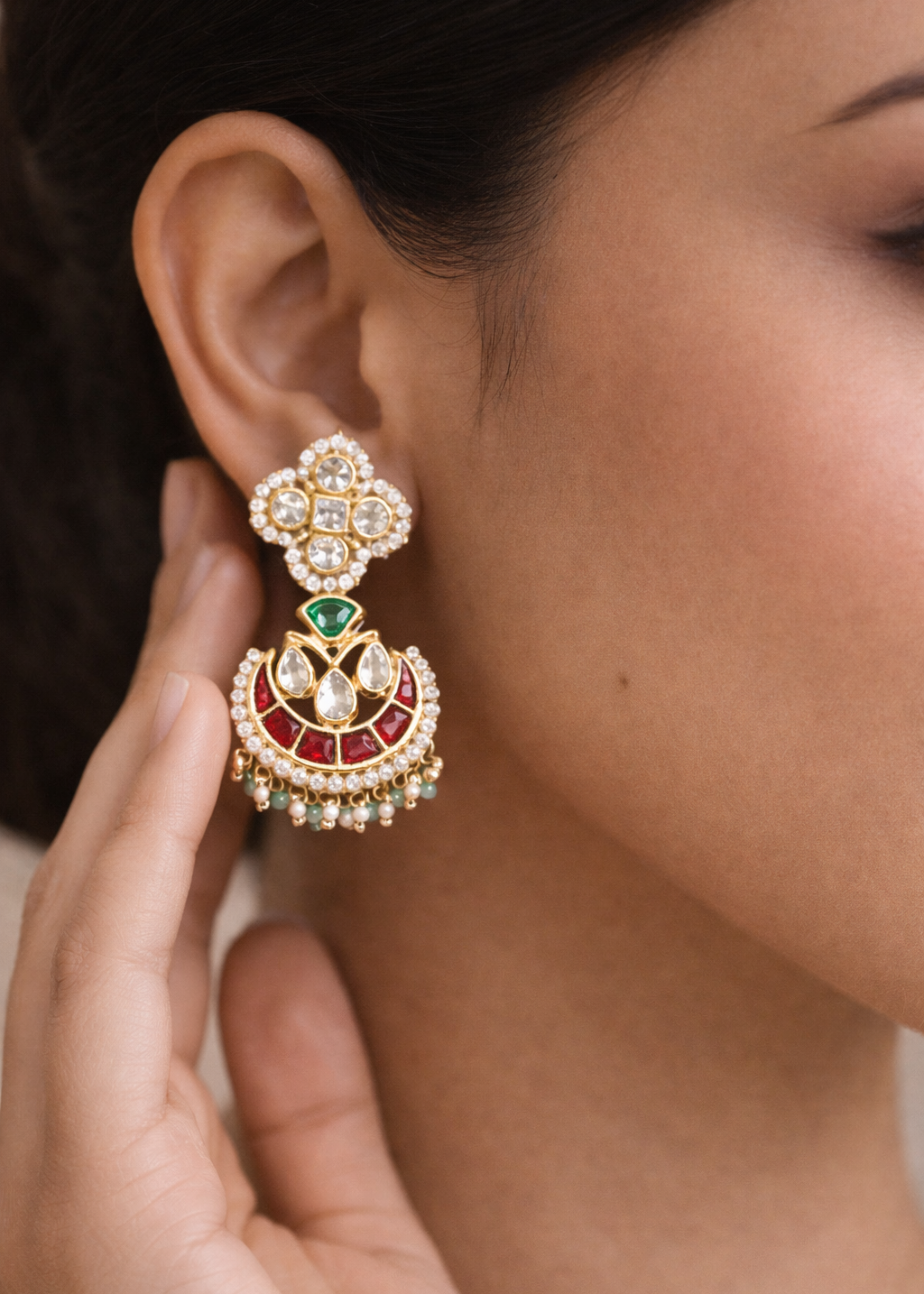 Close-up of a person wearing a decorative earring with a hand adjusting it.