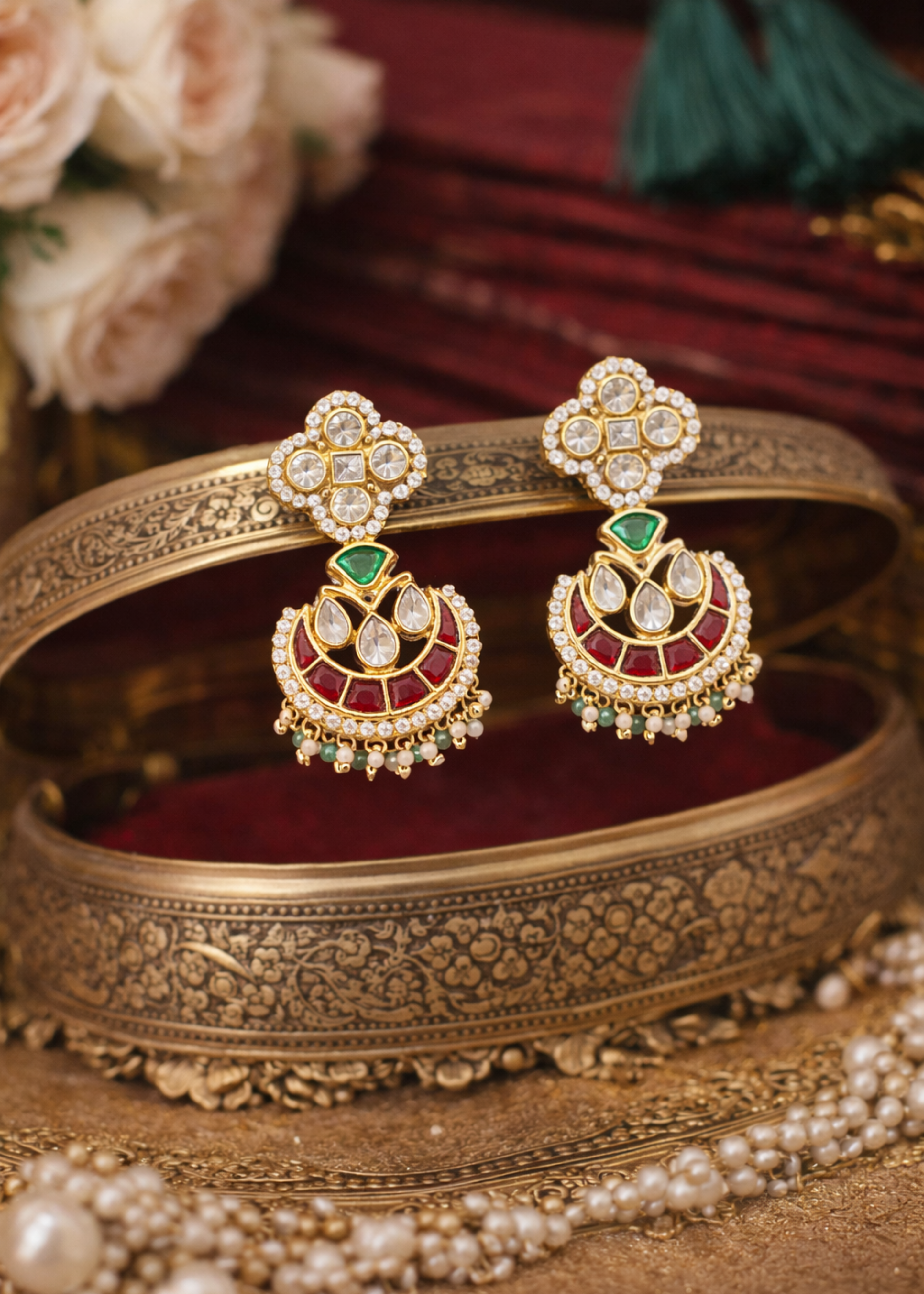 Ornate gold jewelry set with earrings and bangles on a decorative surface.