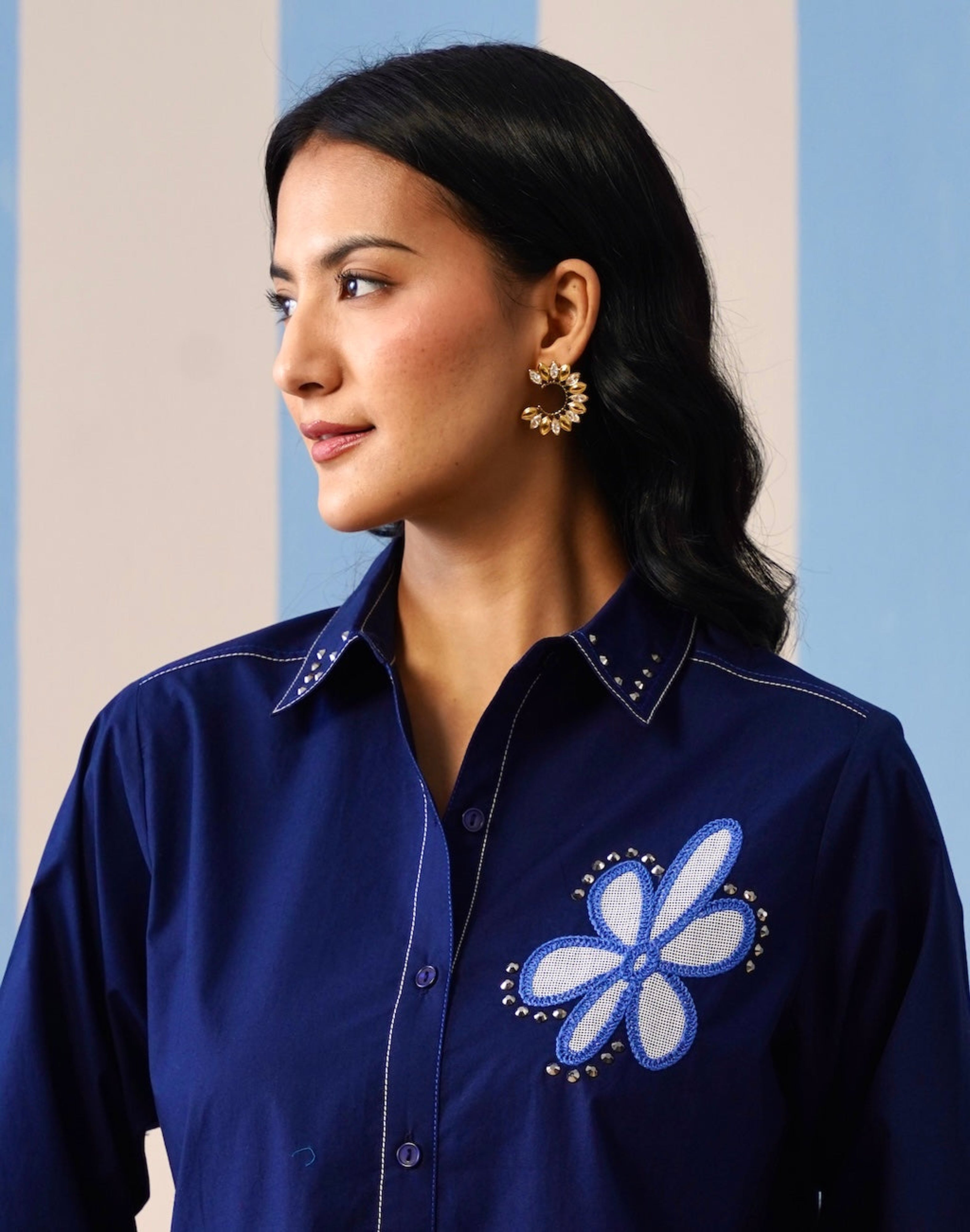 Woman wearing a blue shirt with a floral design against a multicolored background