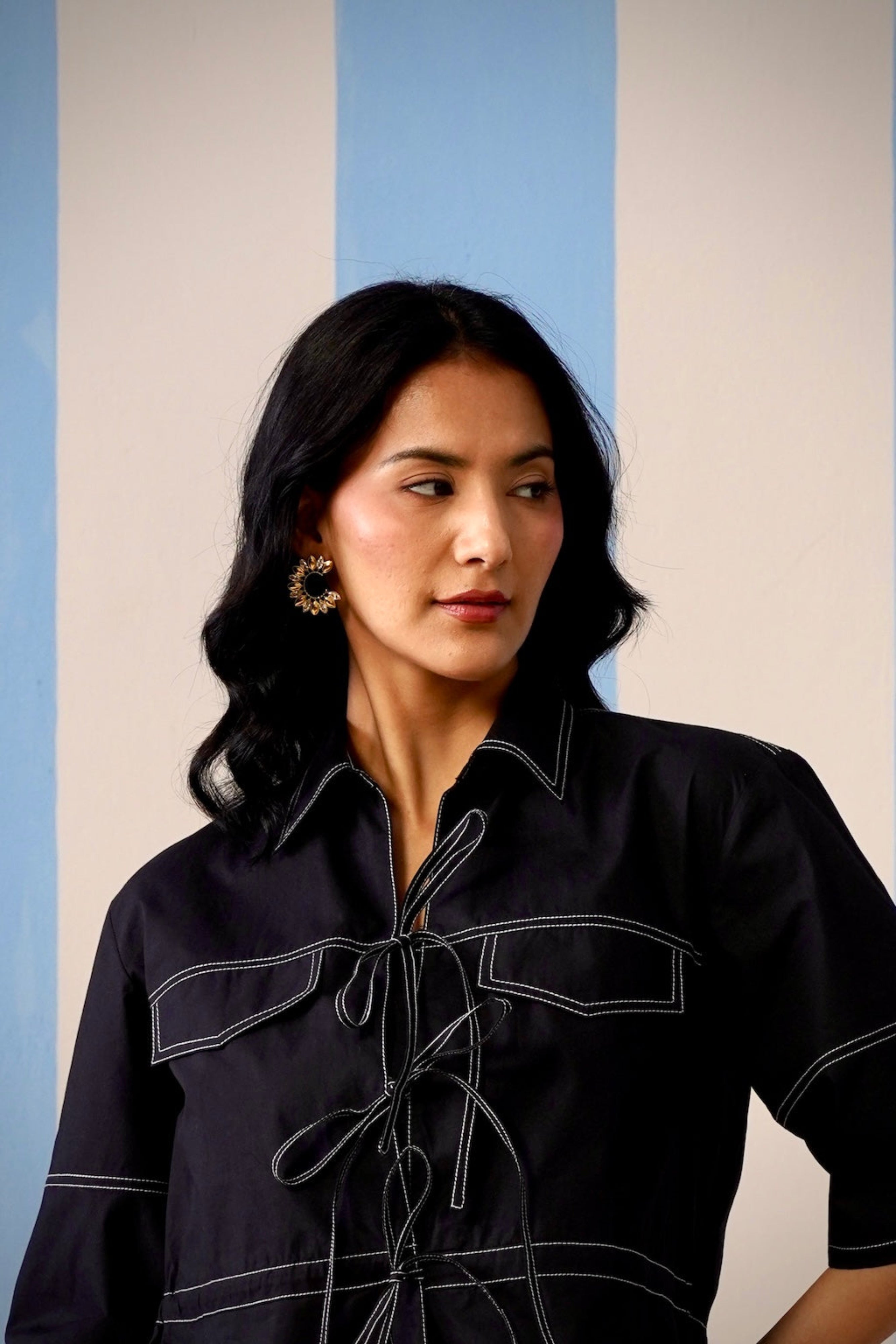 Woman wearing a black outfit with white accents against a blue and beige background