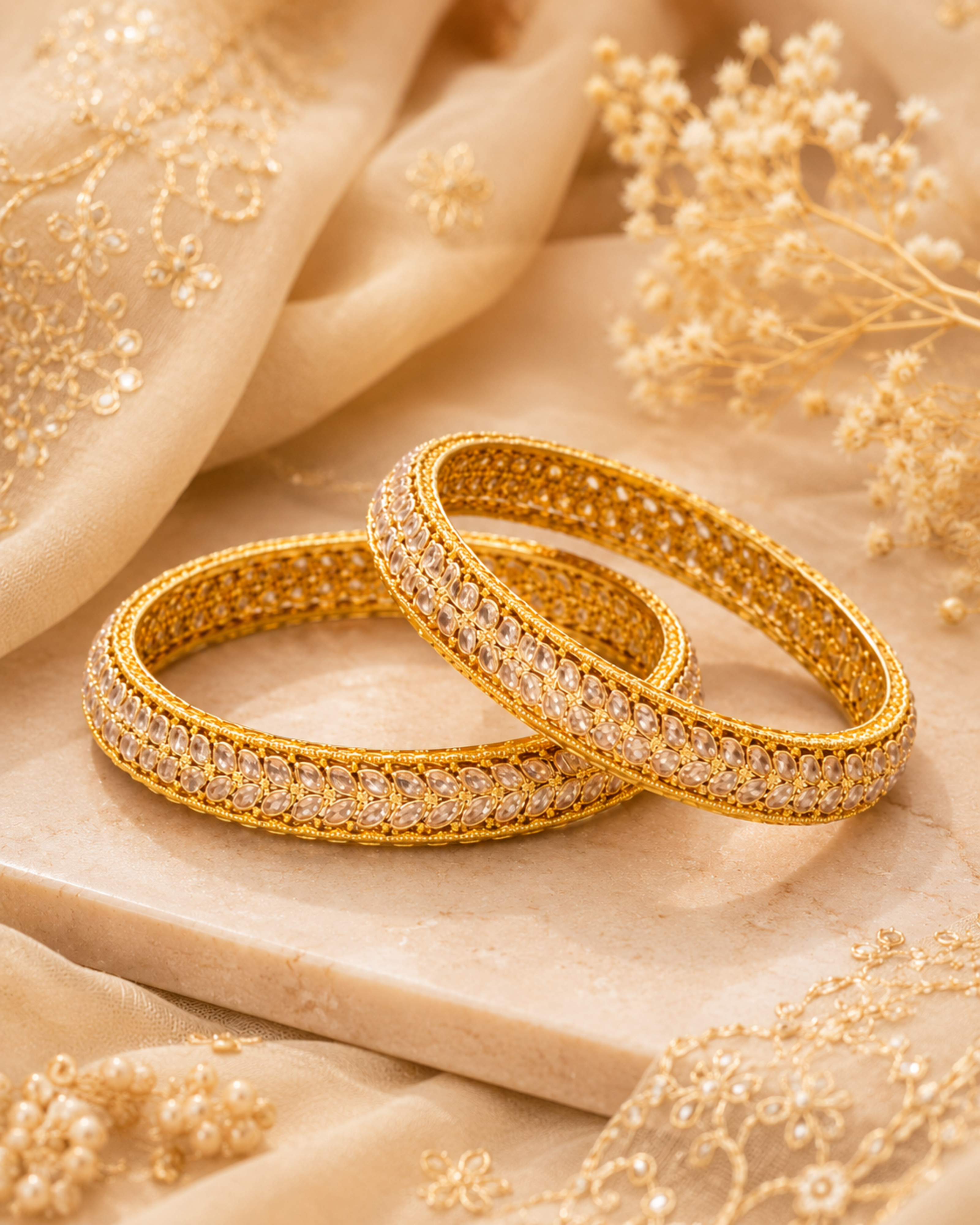 Two gold bangles with diamond accents on a beige fabric background
