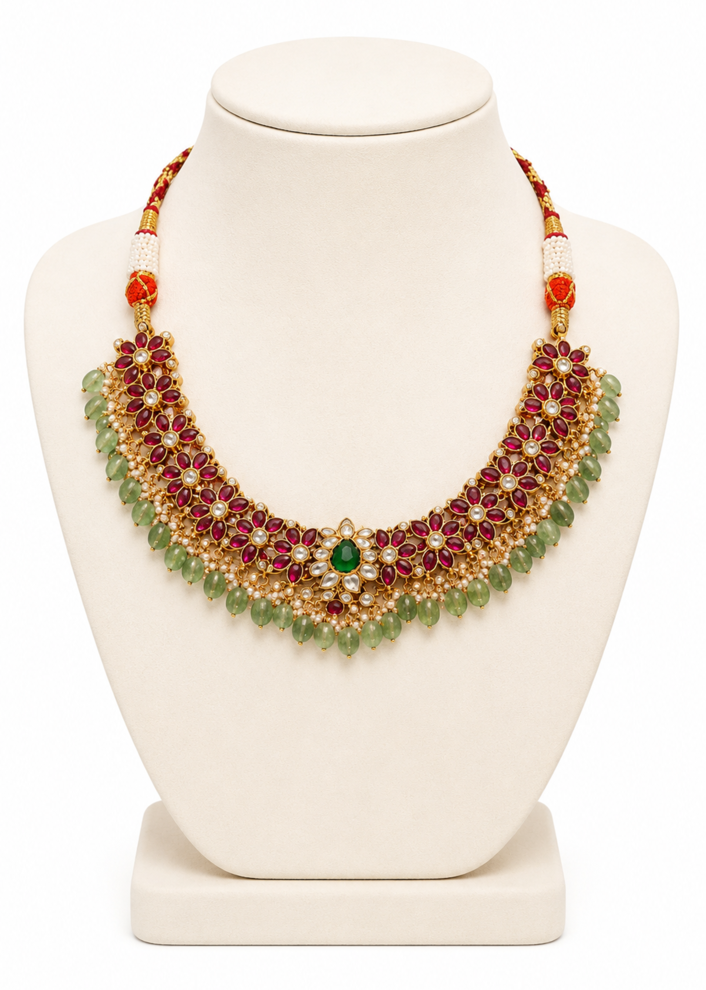 Ornate necklace with red and green stones on a white mannequin bust