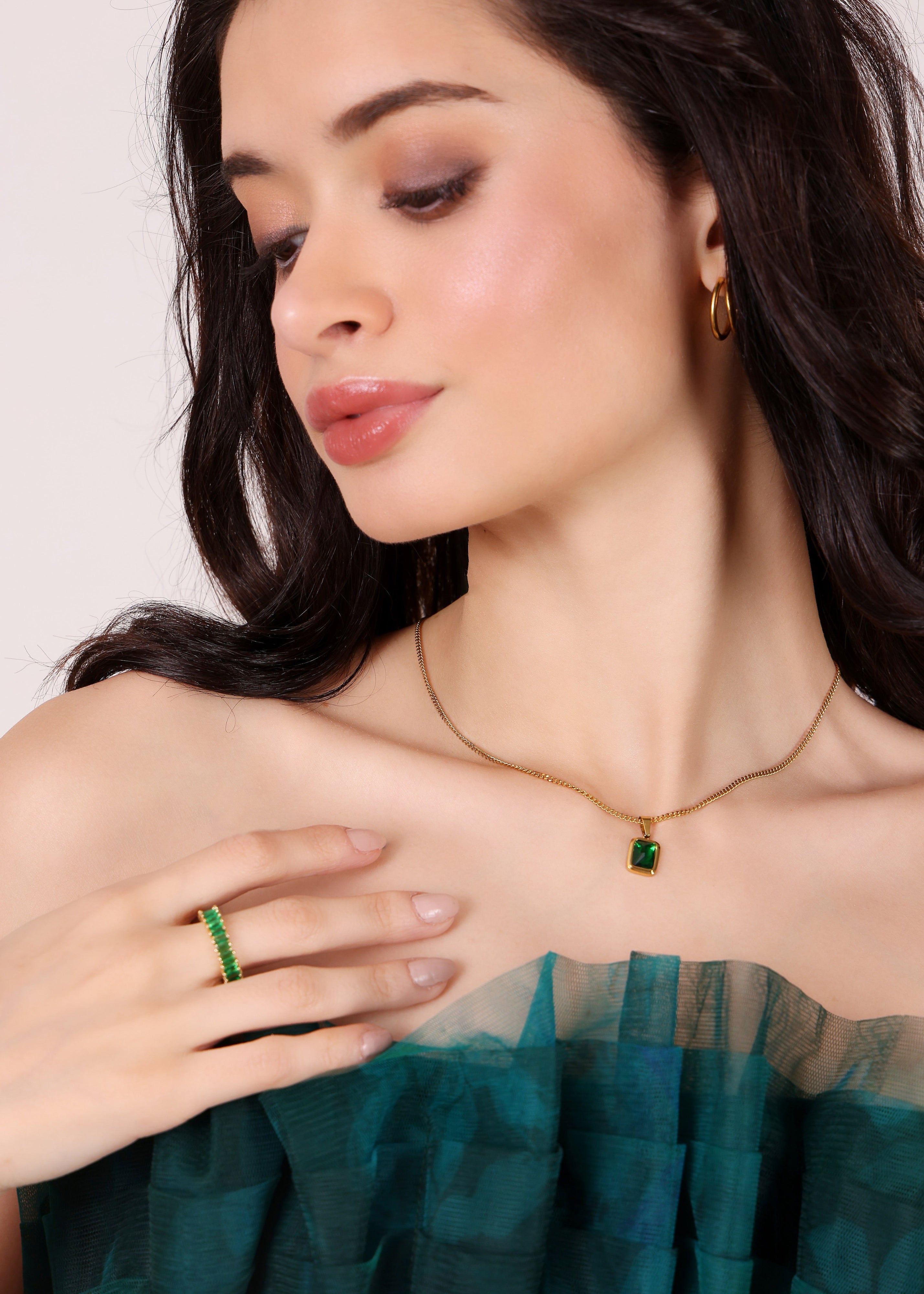 Woman wearing green jewelry against a neutral background