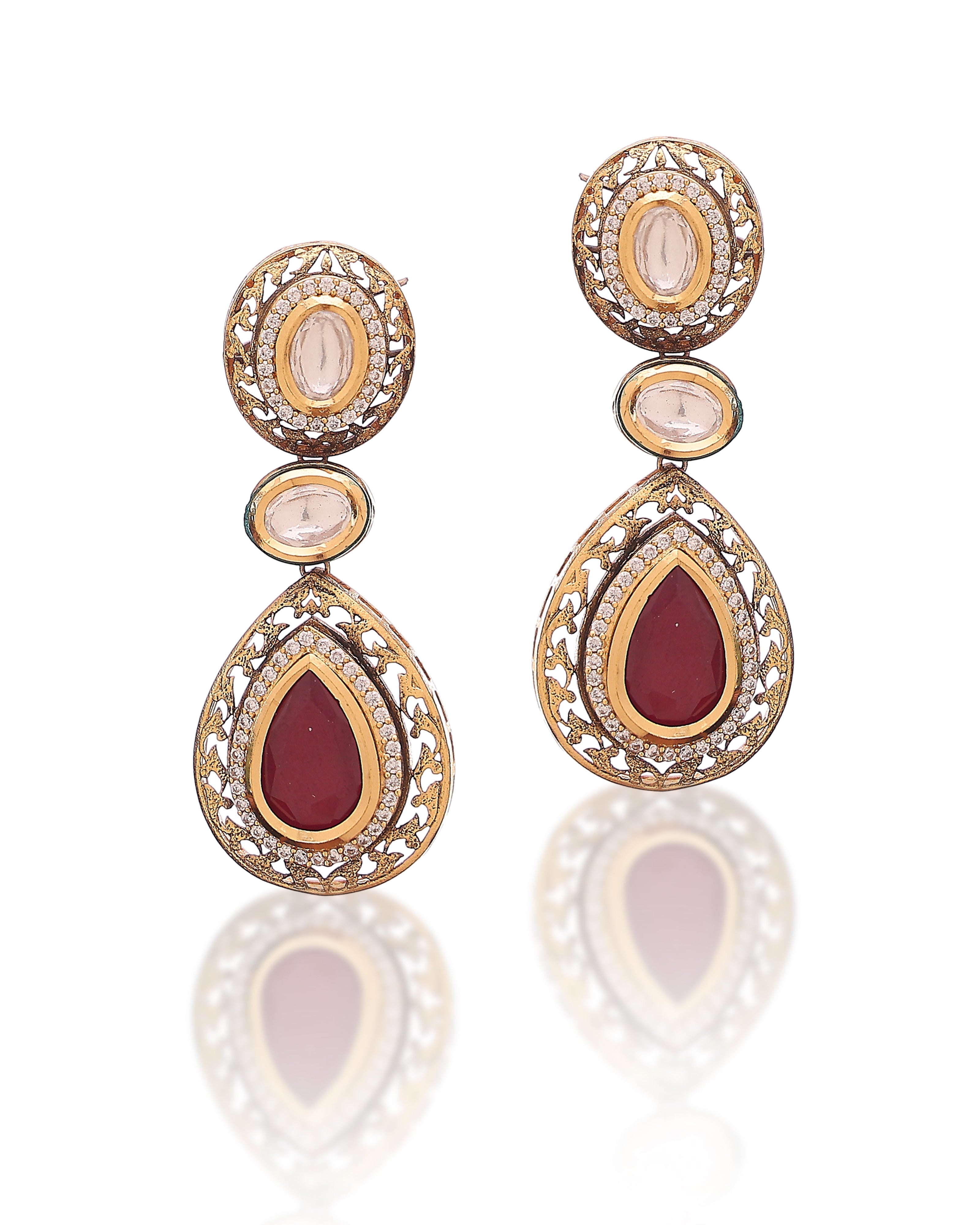 Pair of gold earrings with red and clear gemstones on a white background