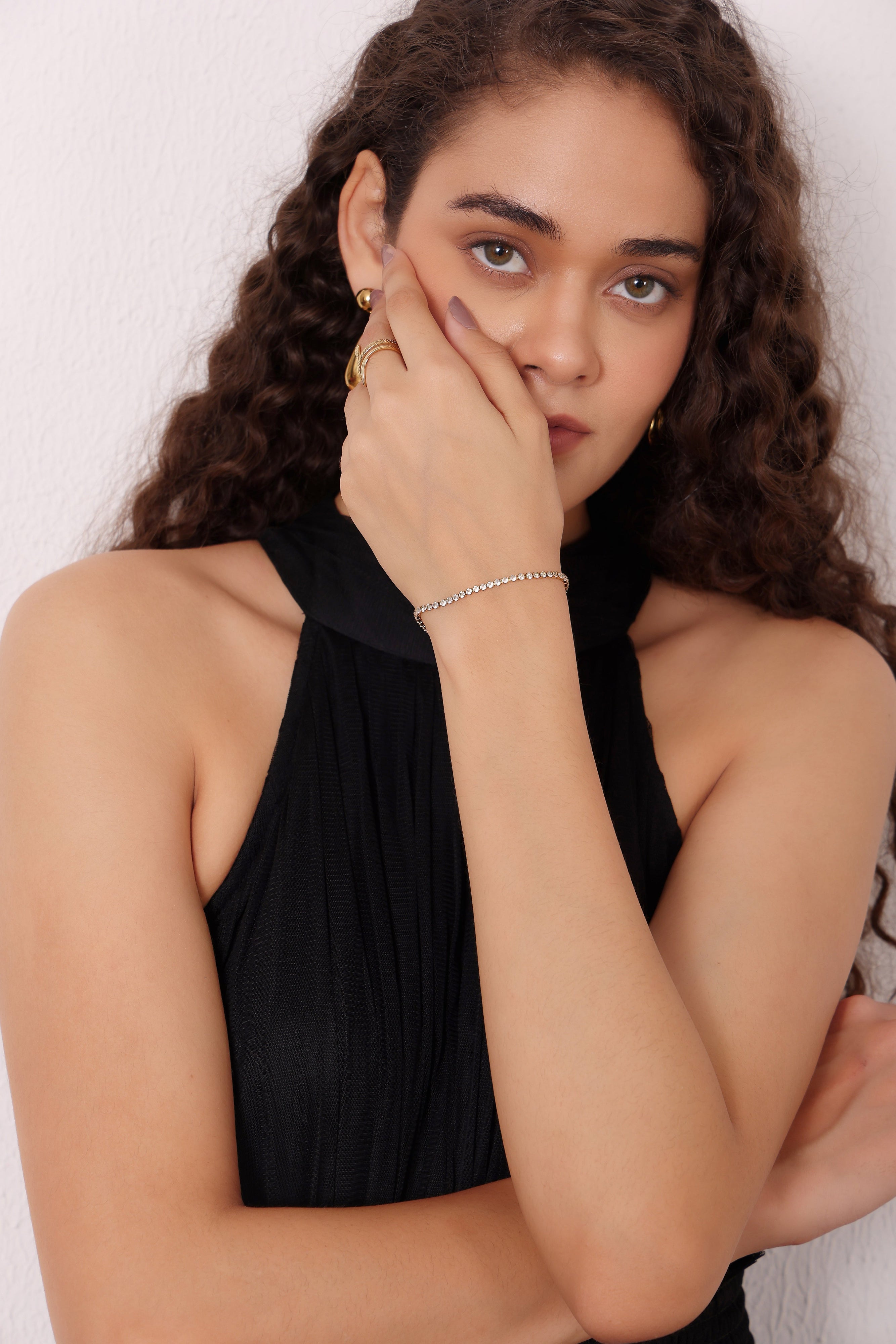 Woman wearing a black halter top with jewelry against a white background