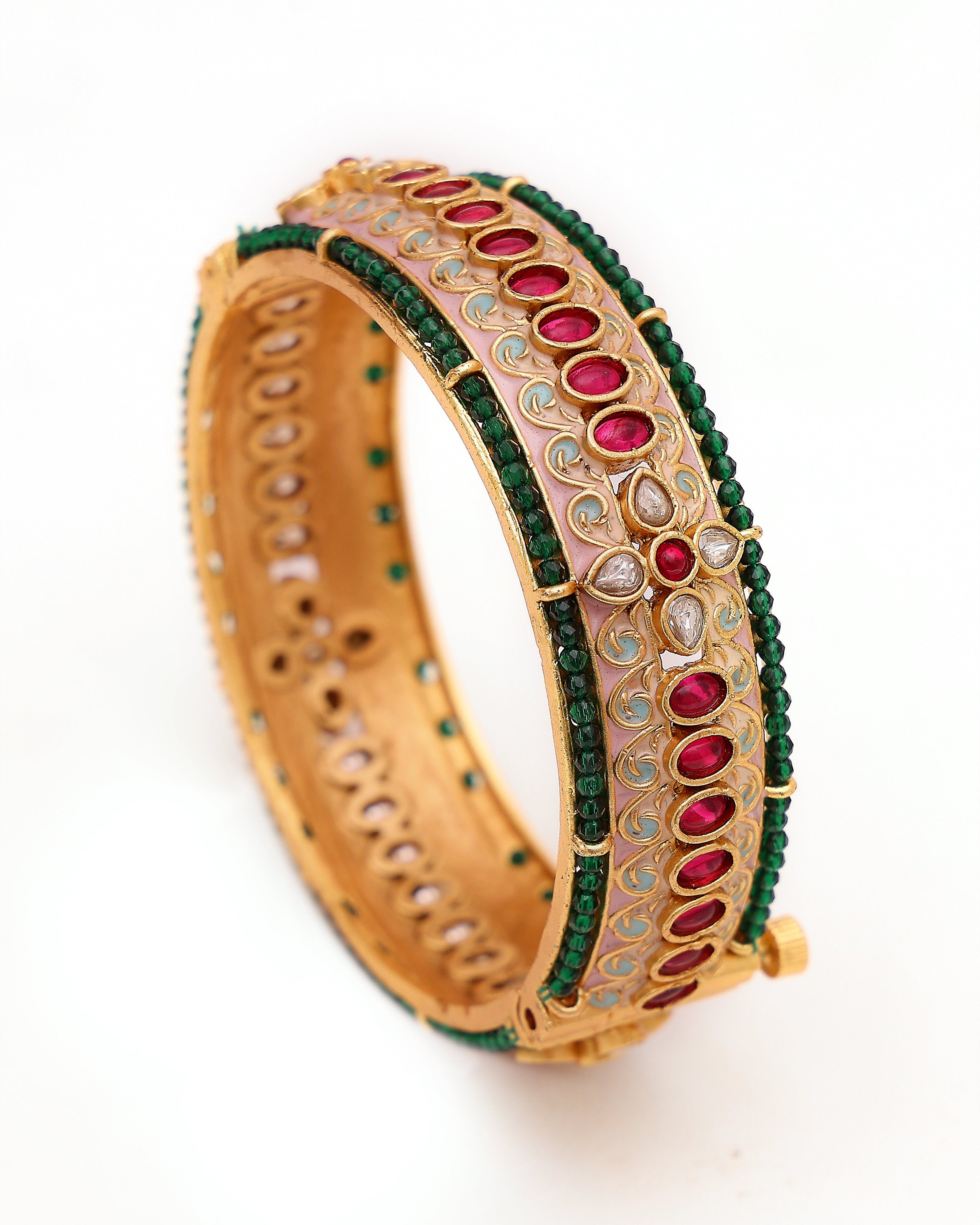 Gold bangle with green and red stones on a white background