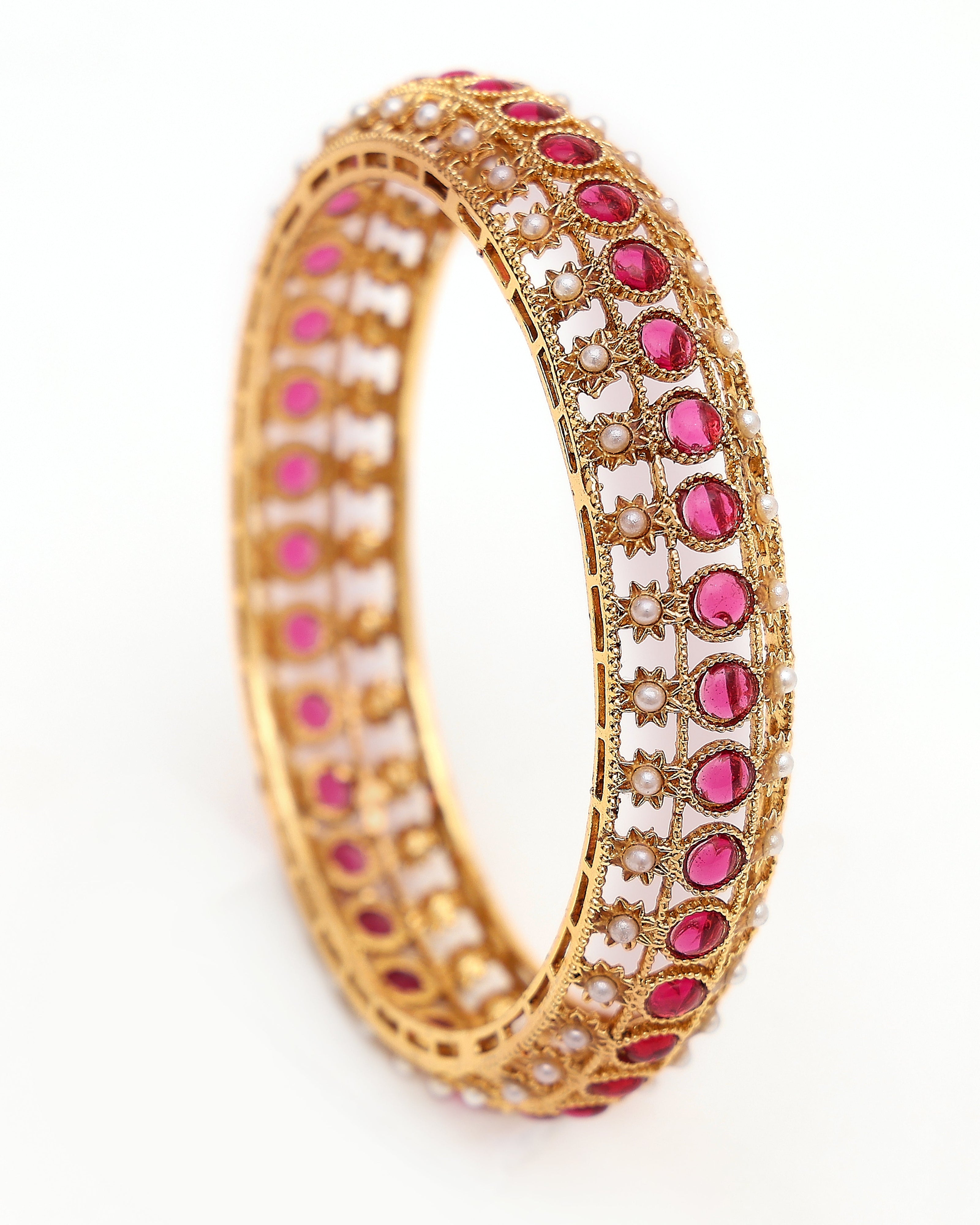 Gold bracelet with pink stones and pearls on a white background