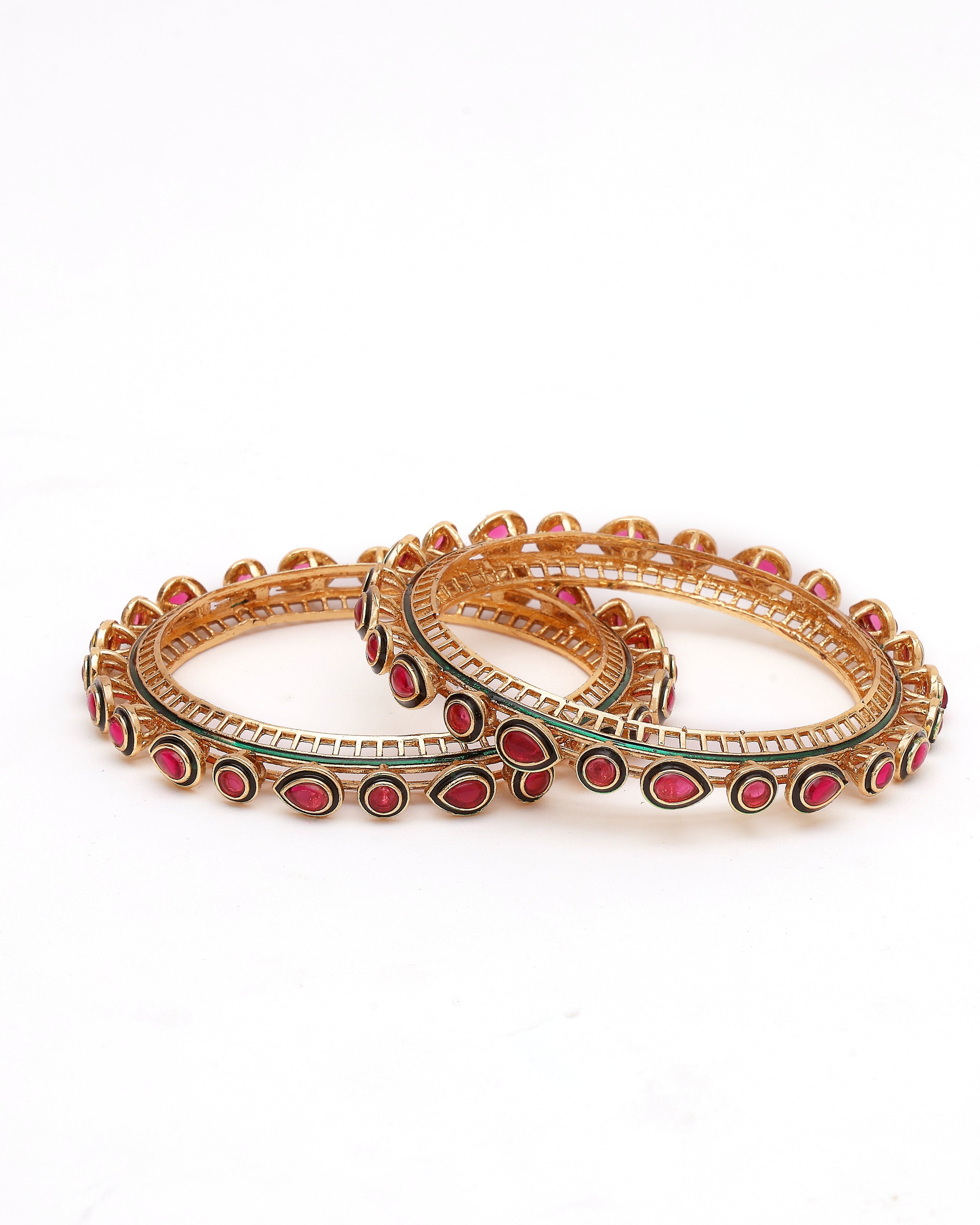 Pair of gold bangles with red stones on a white background