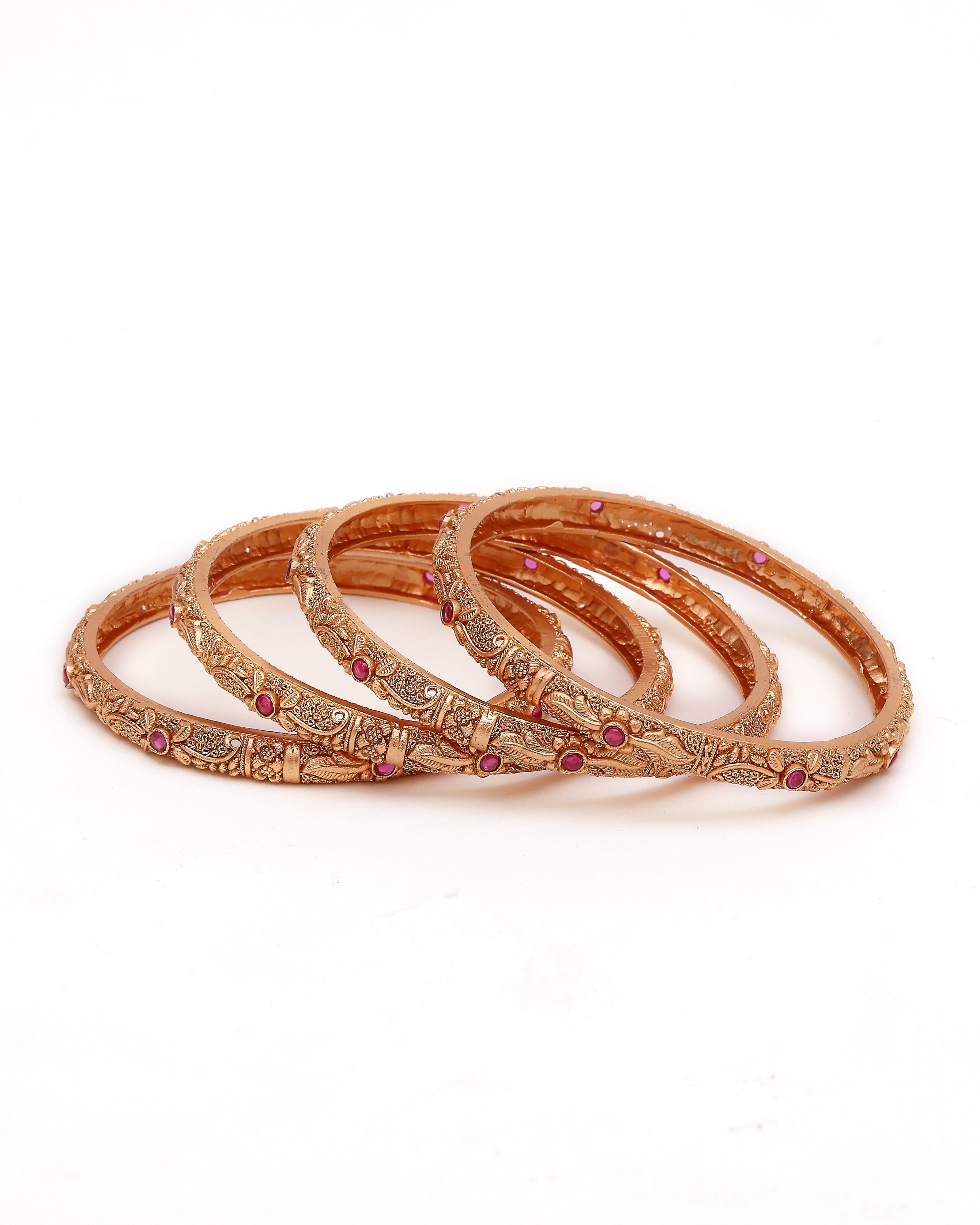 Set of rose gold bangles with pink stones on a white background