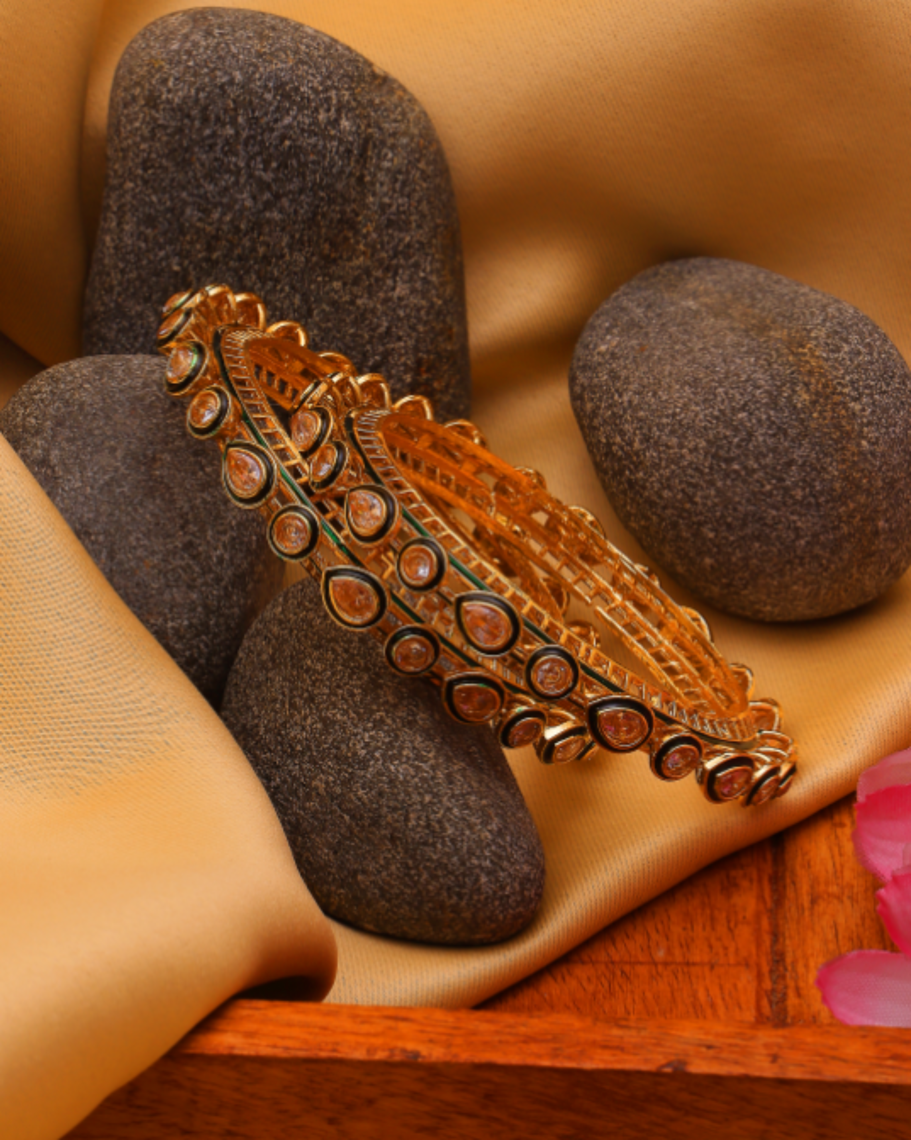 Decorative orange bracelet on a wooden surface with stones