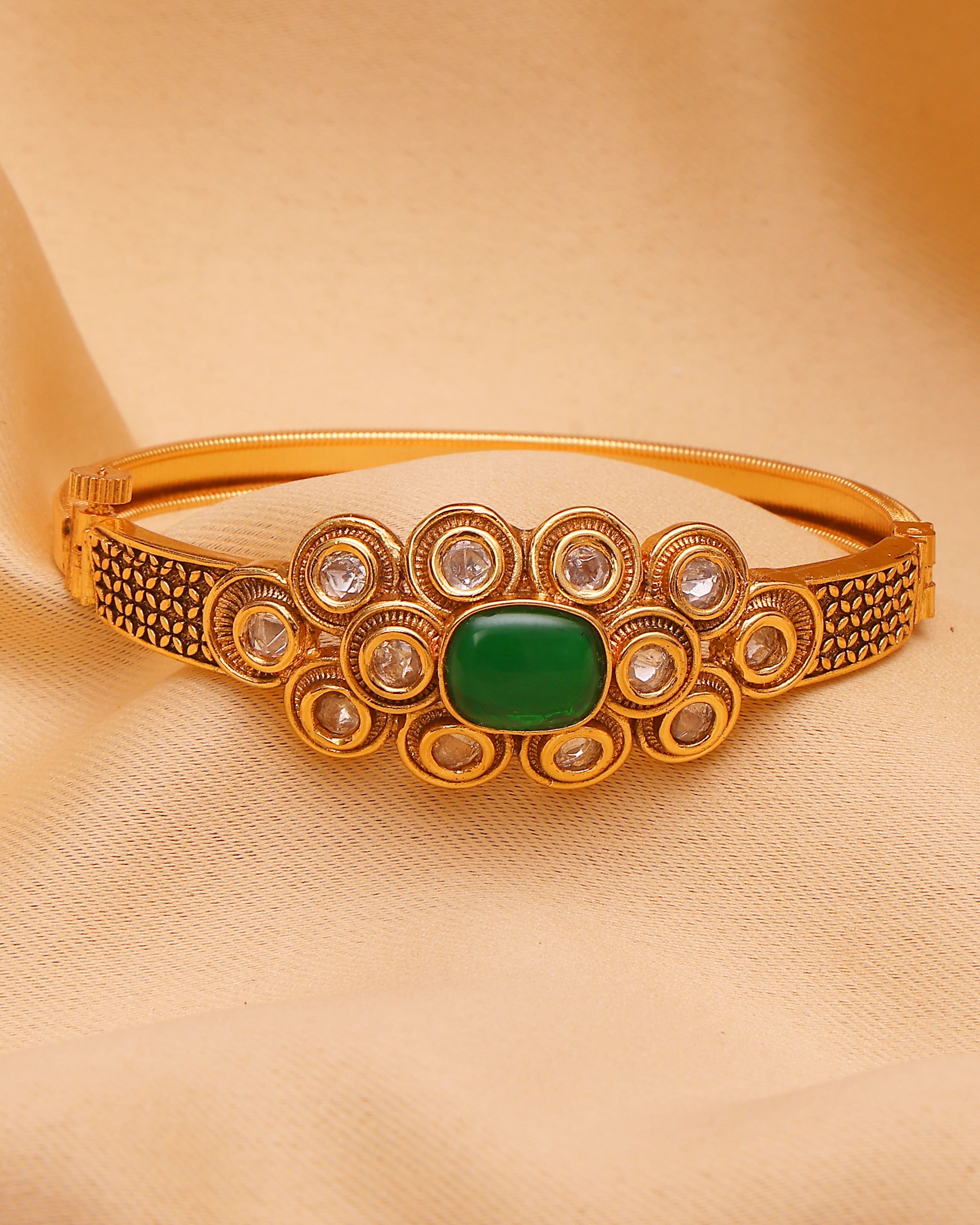 Gold bracelet with green gemstone on a beige background