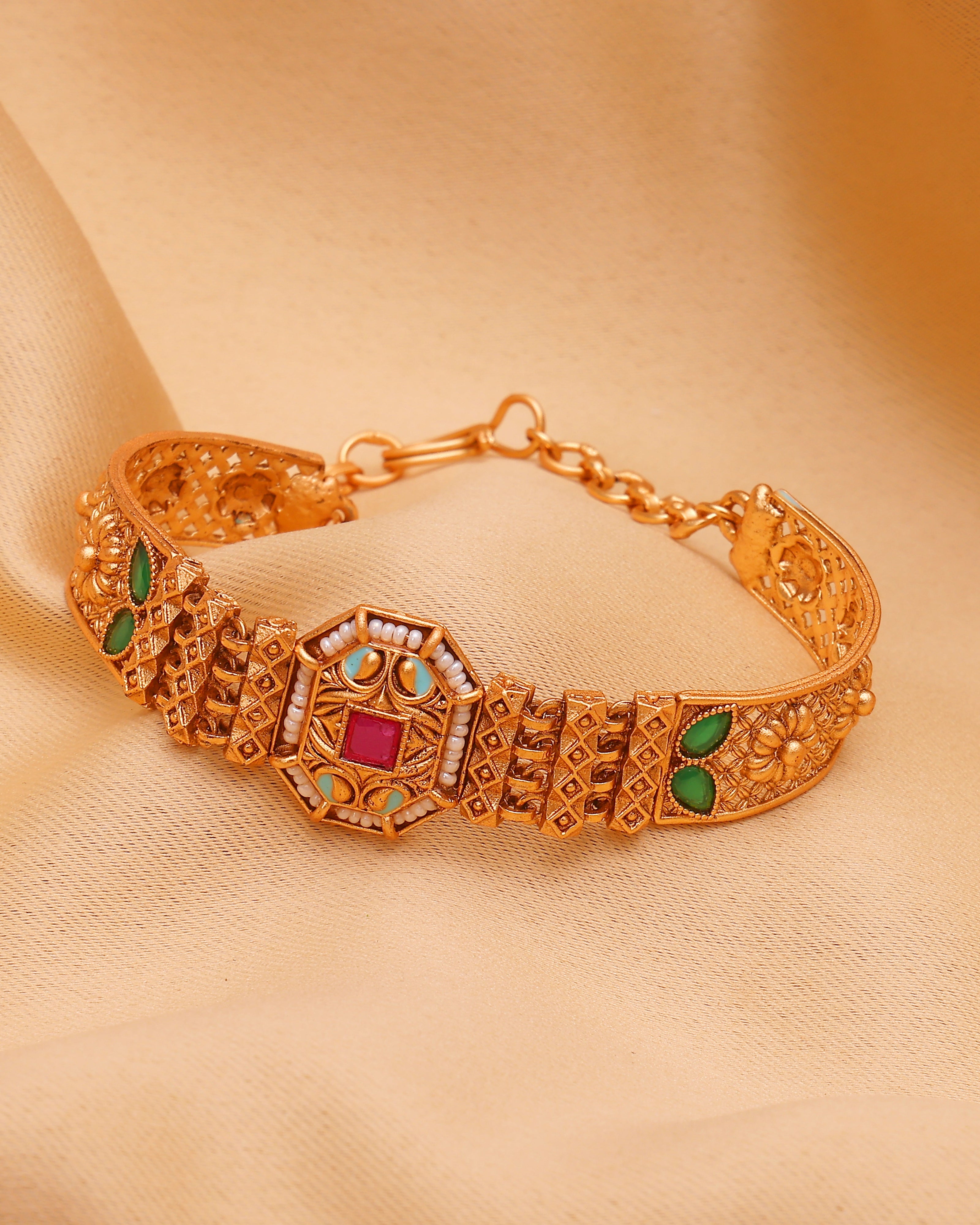 Gold bracelet with gemstones on a beige fabric background