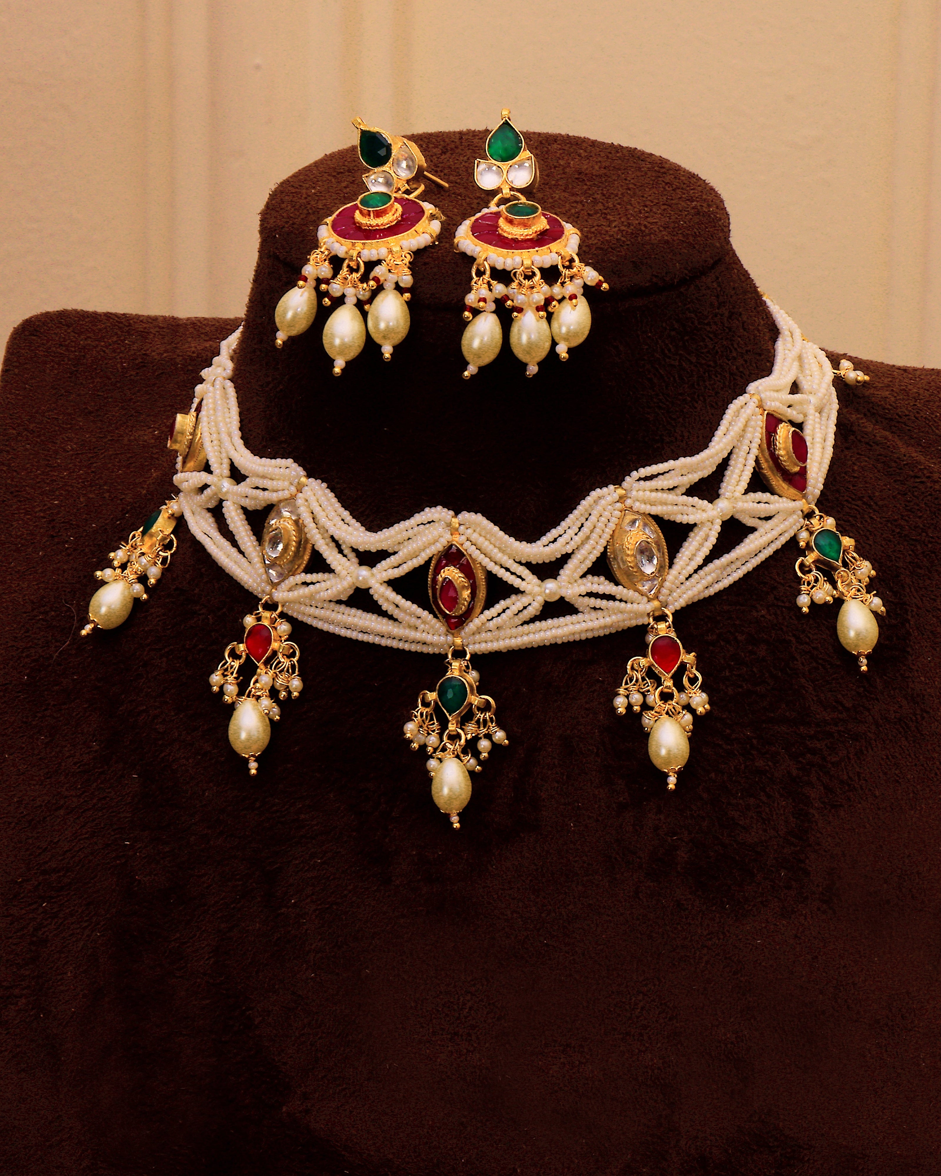 Ornate necklace with matching earrings on a brown stand