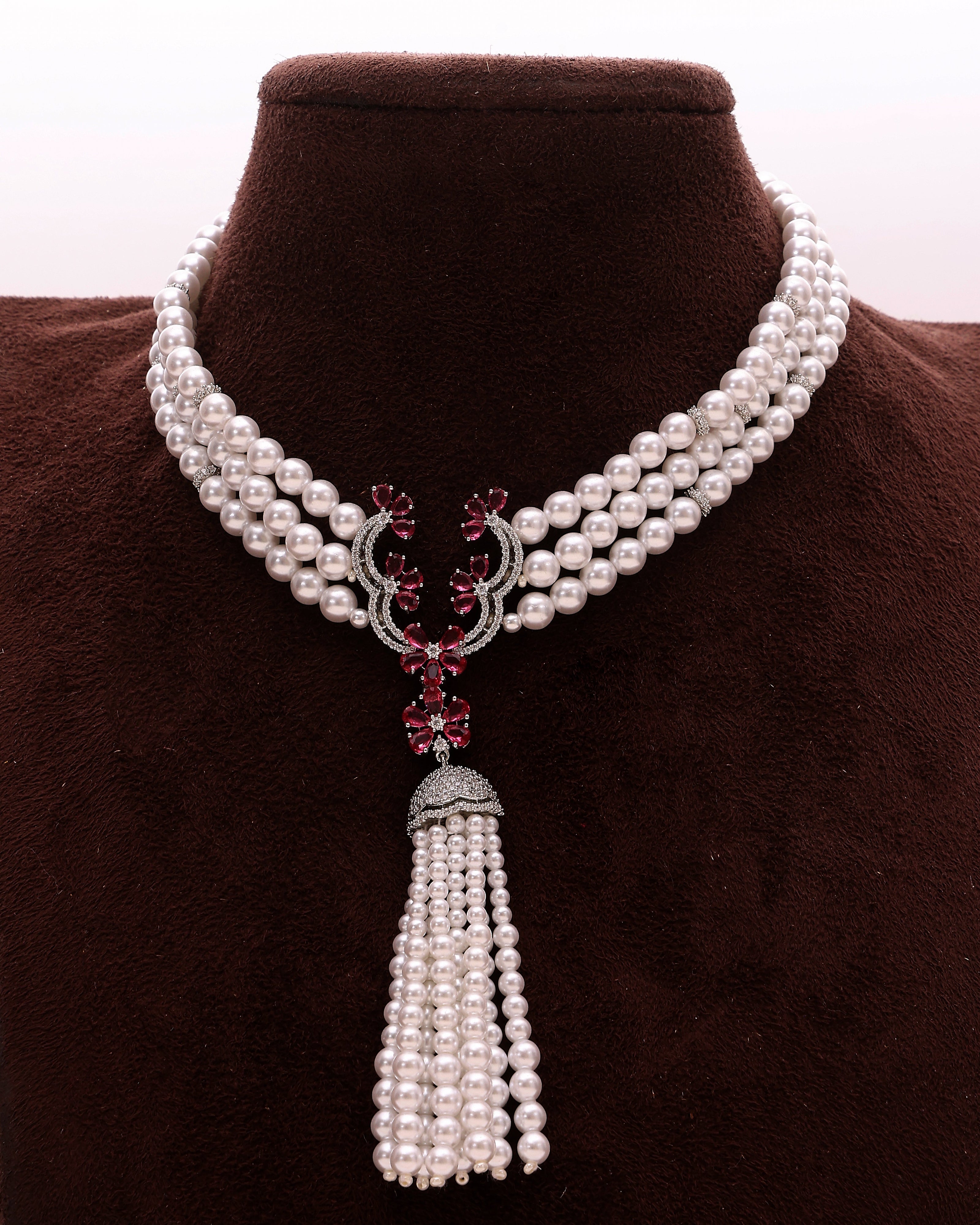 Pearl necklace with a tassel pendant on a brown velvet stand