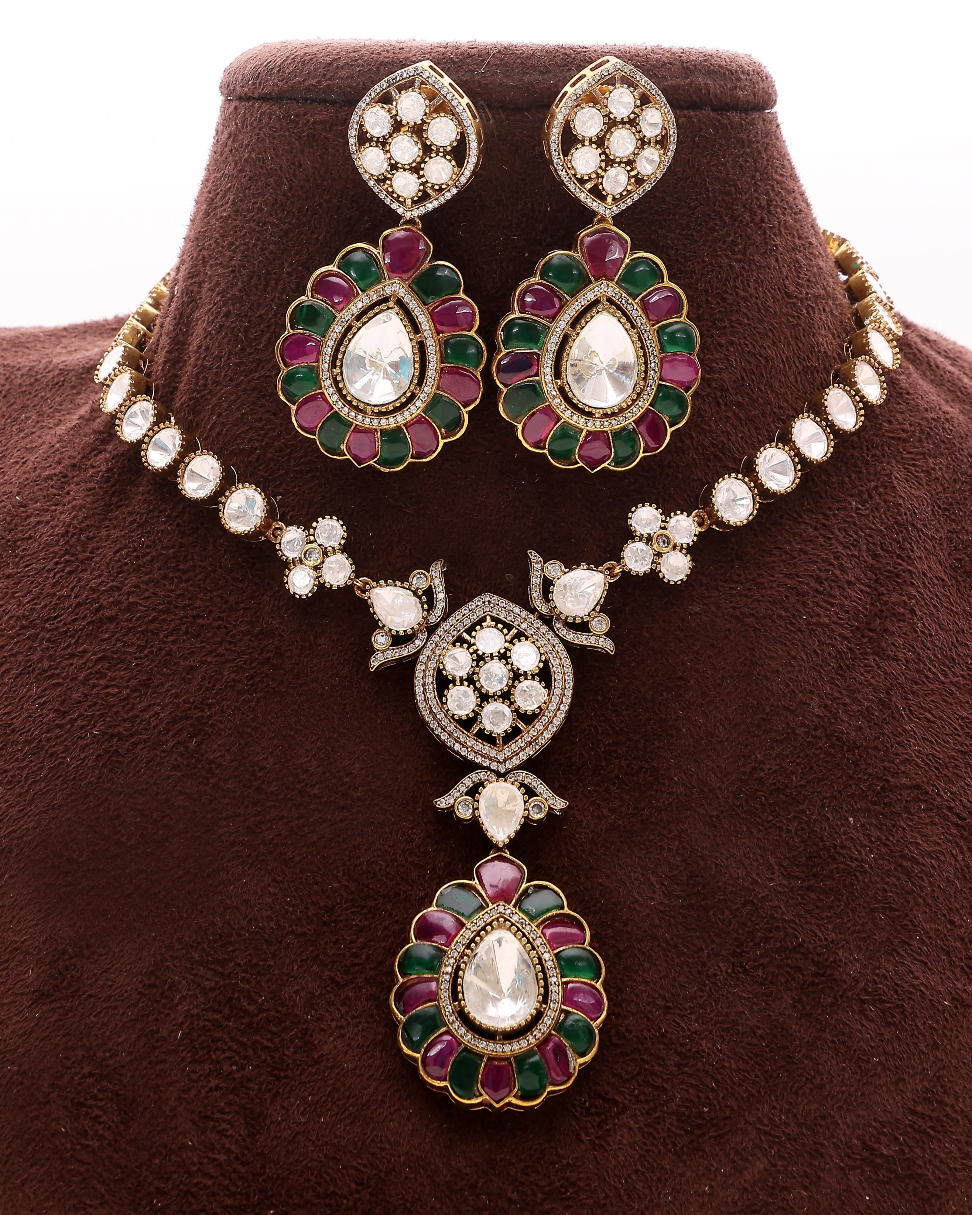 Ornate necklace and earrings set on a brown velvet stand