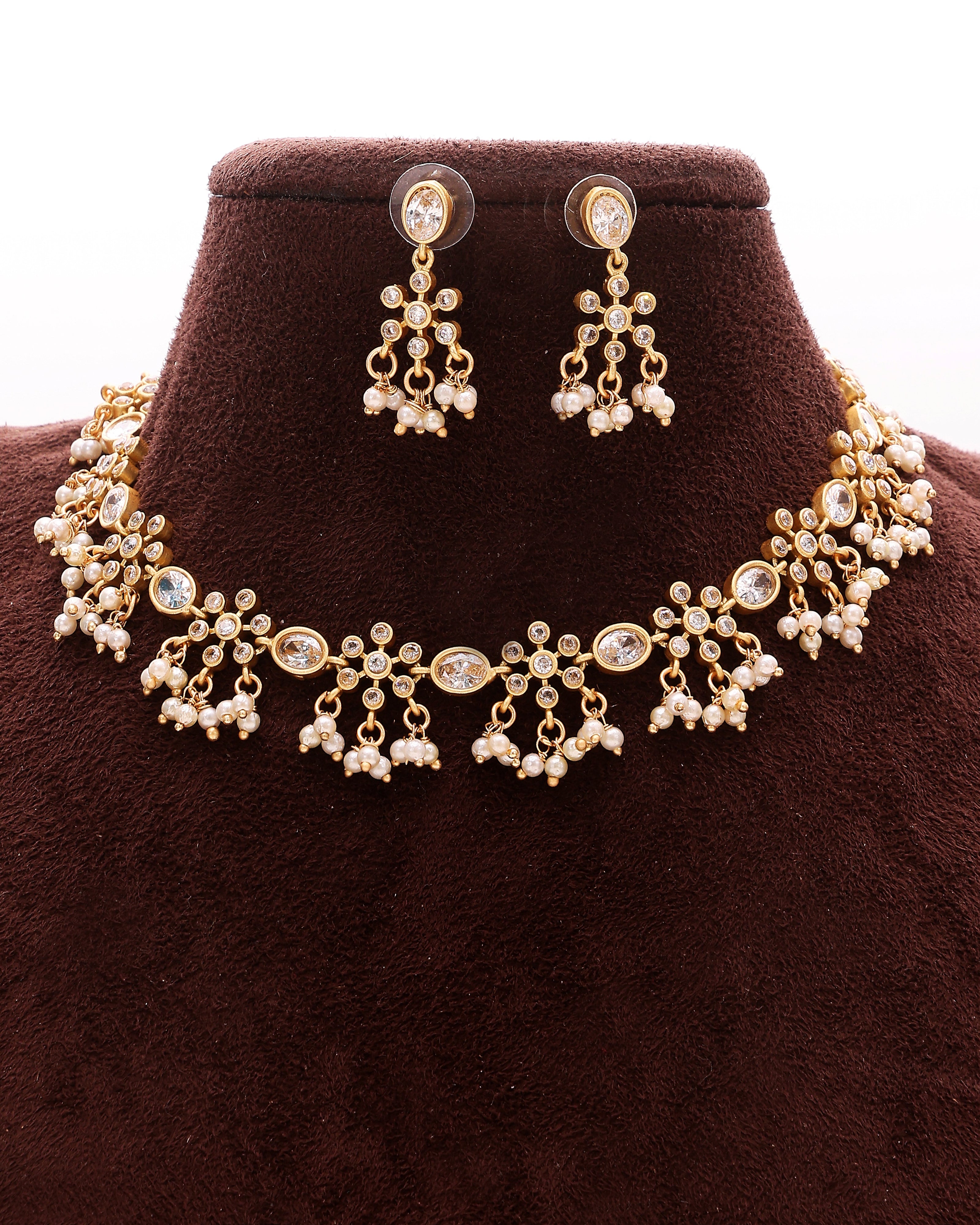 Gold necklace and earrings set on a brown velvet stand