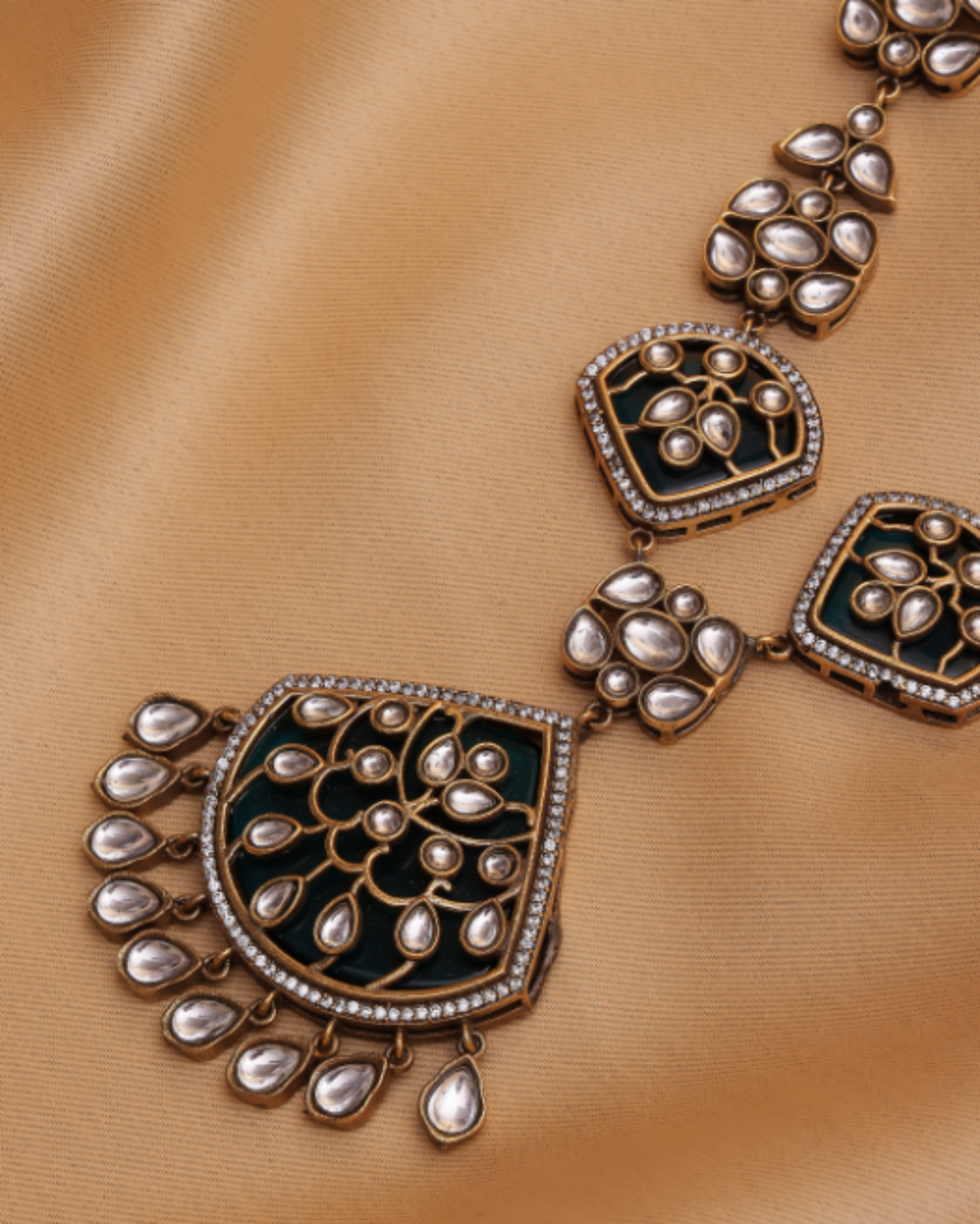 Ornate necklace with black and gold design on a beige fabric background