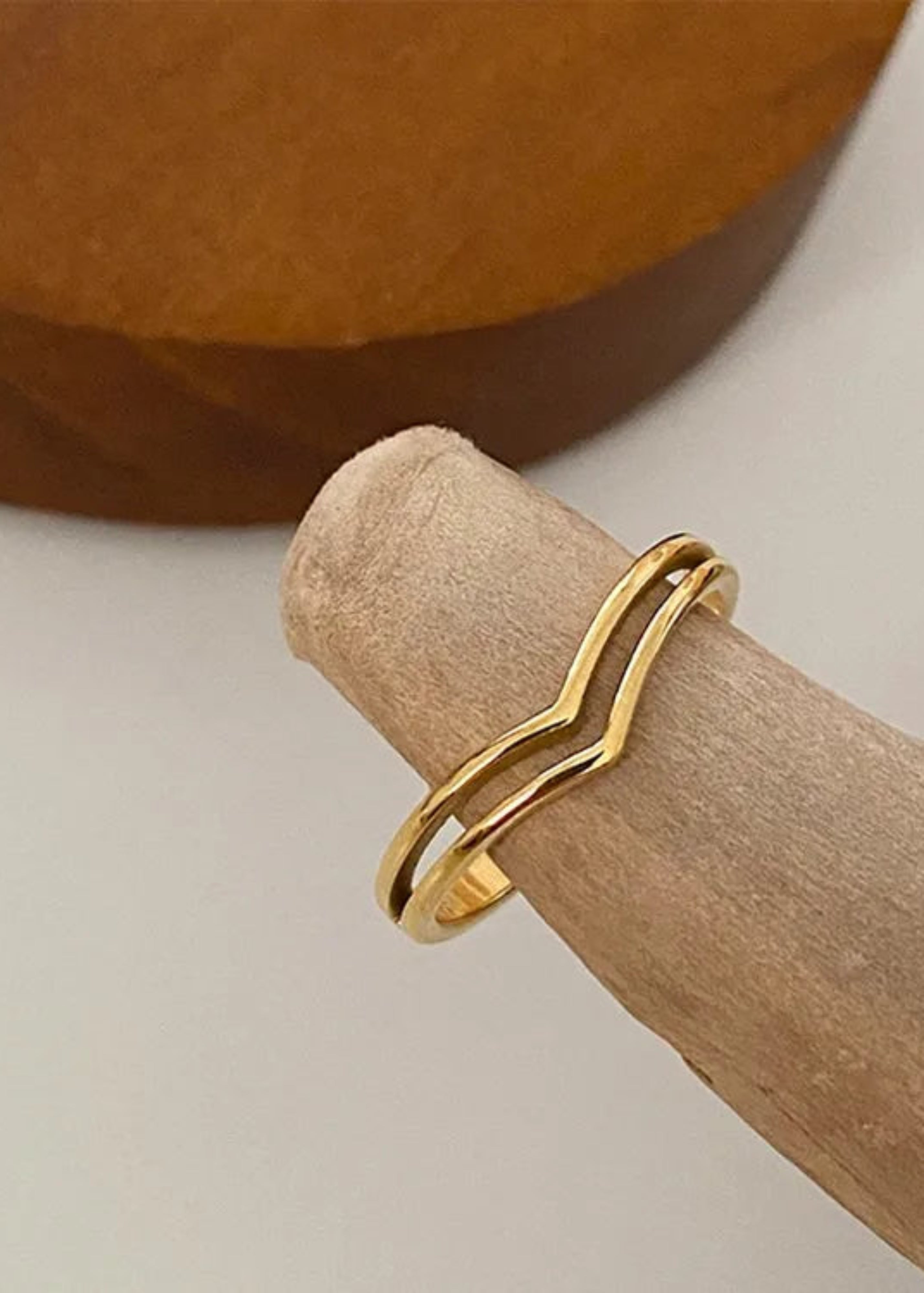 Gold ring on a wooden block with a neutral background