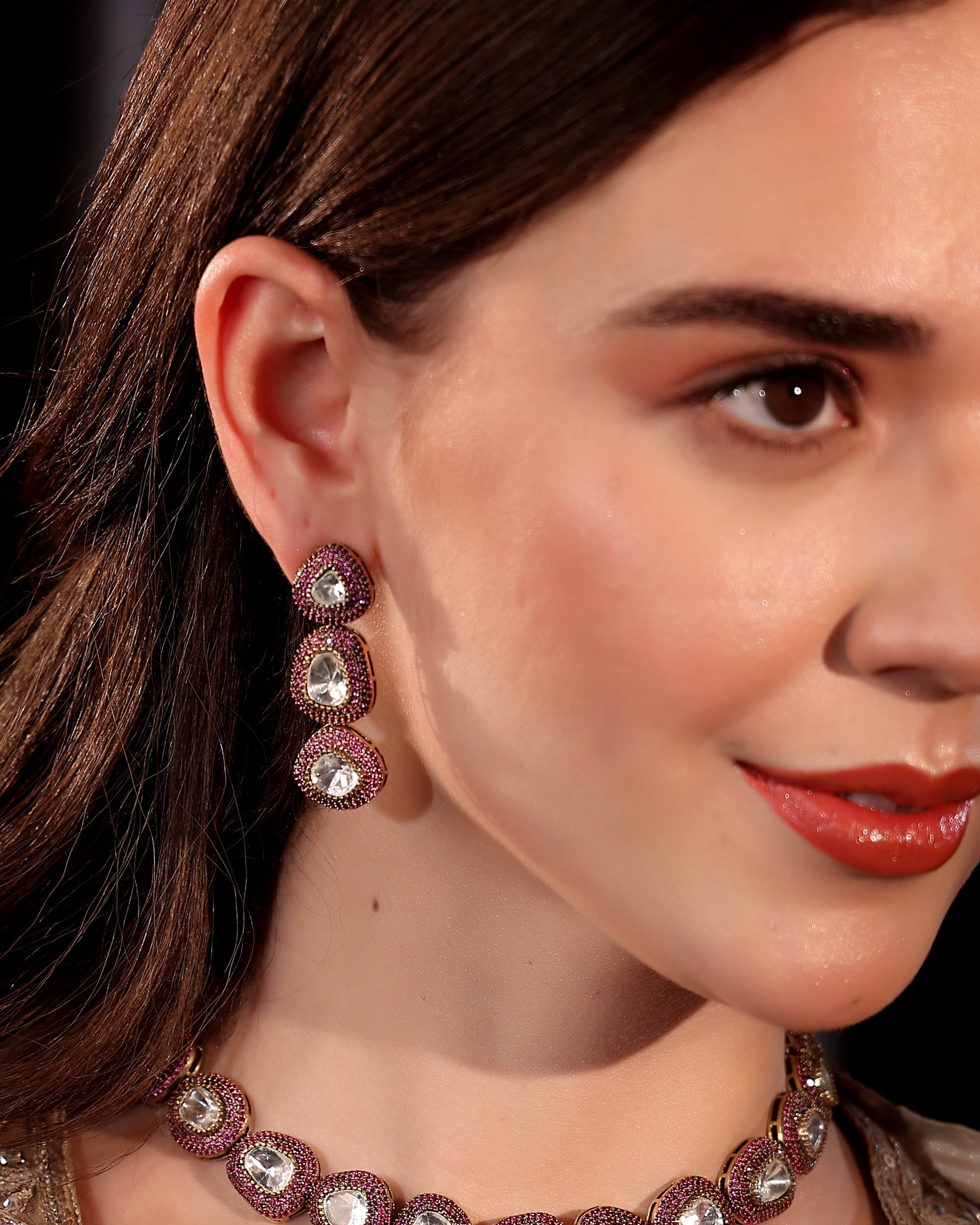 Close-up of a woman wearing a necklace and earrings with a dark background