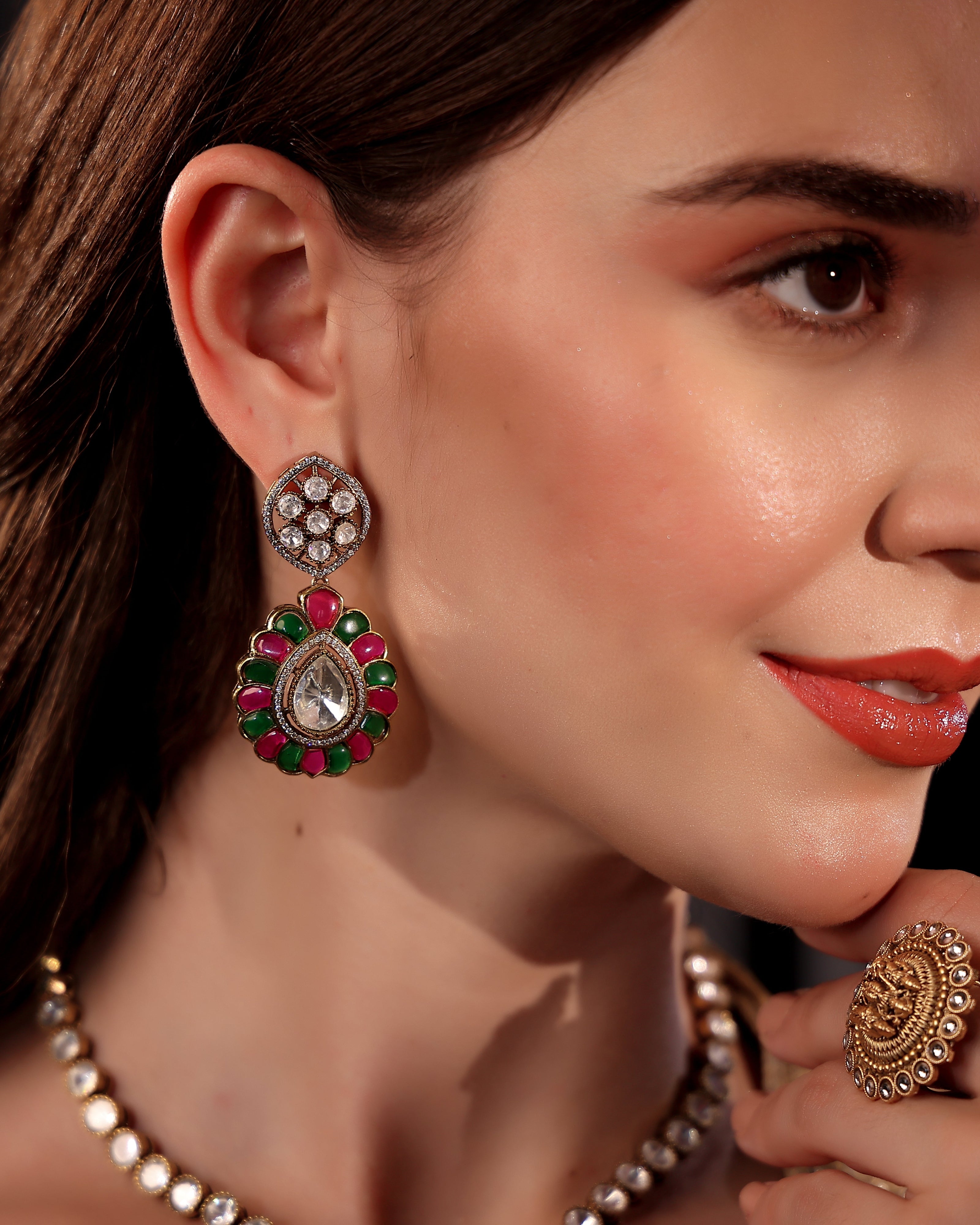 Close-up of a woman wearing ornate earrings and a ring, with a focus on the jewelry.