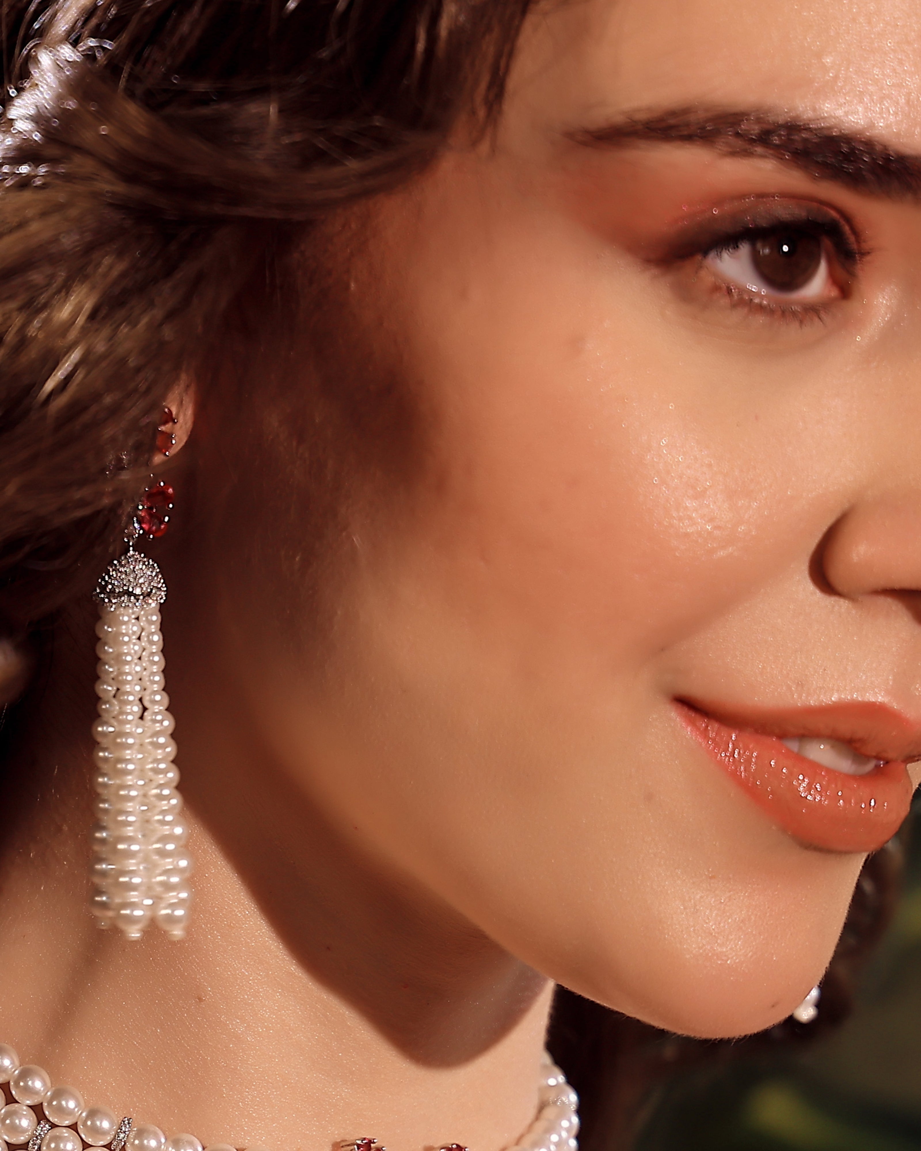 Close-up of a woman wearing pearl earrings with a blurred background
