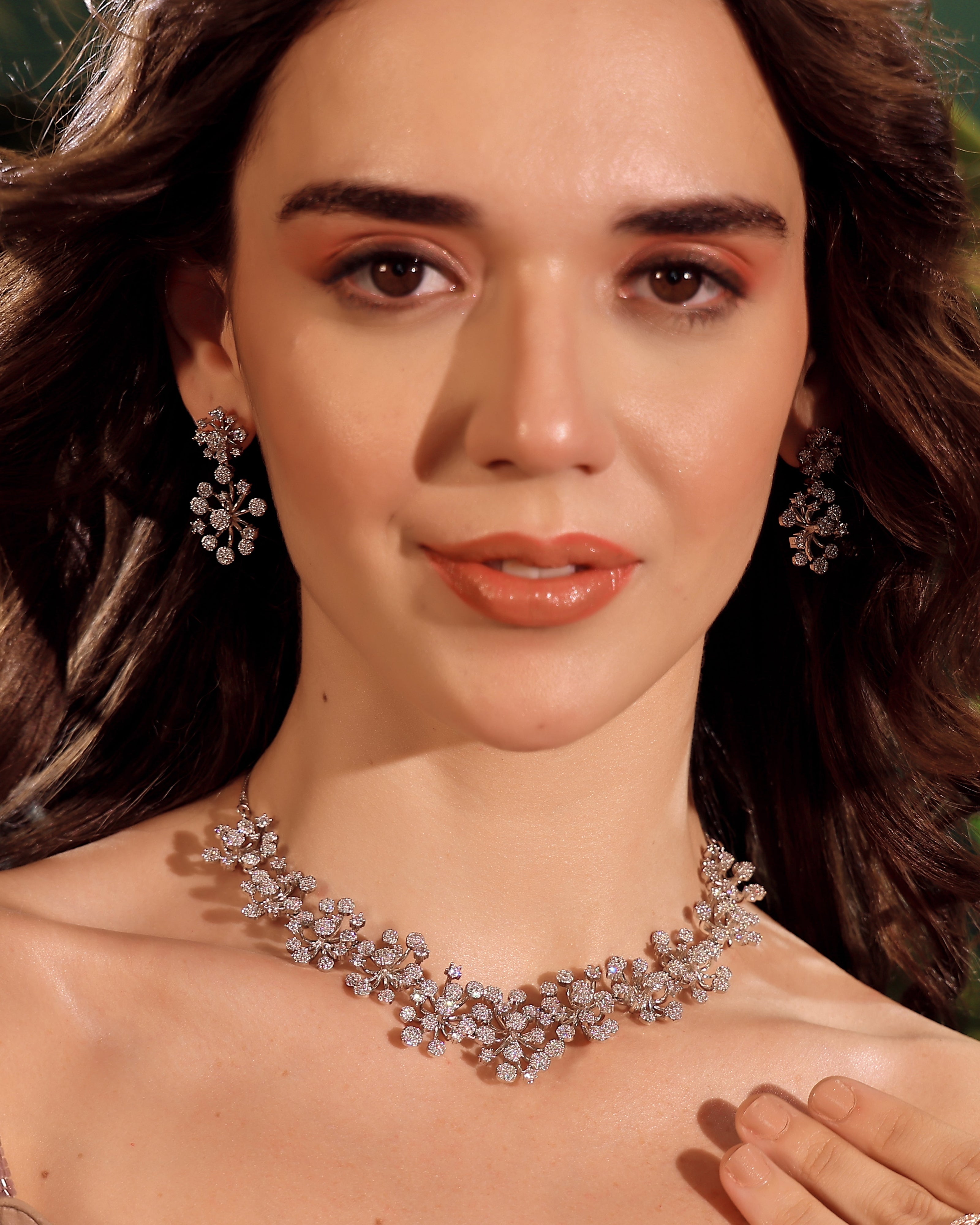 Woman wearing a diamond necklace and earrings with a blurred background