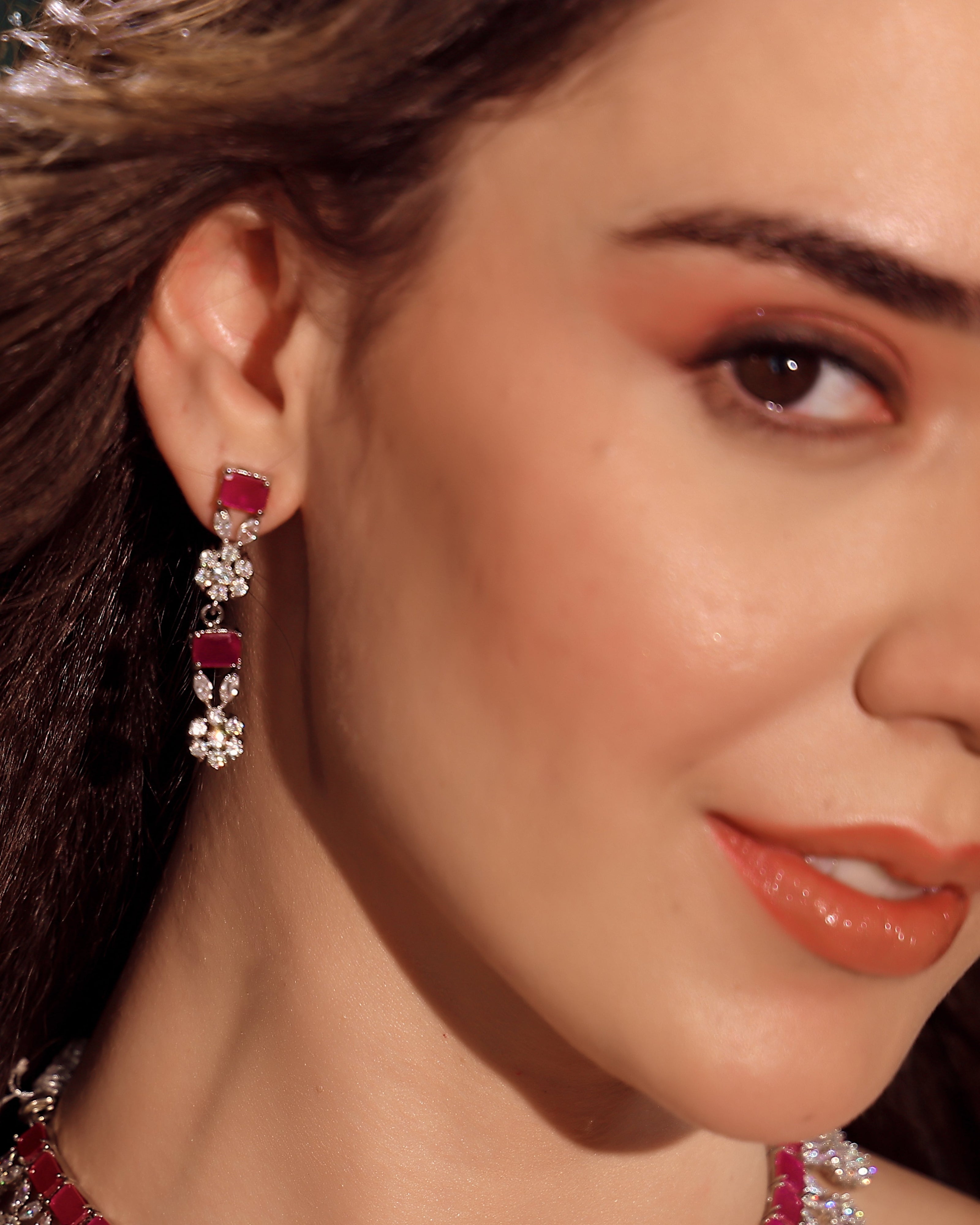 Close-up of a woman wearing red and silver earrings.