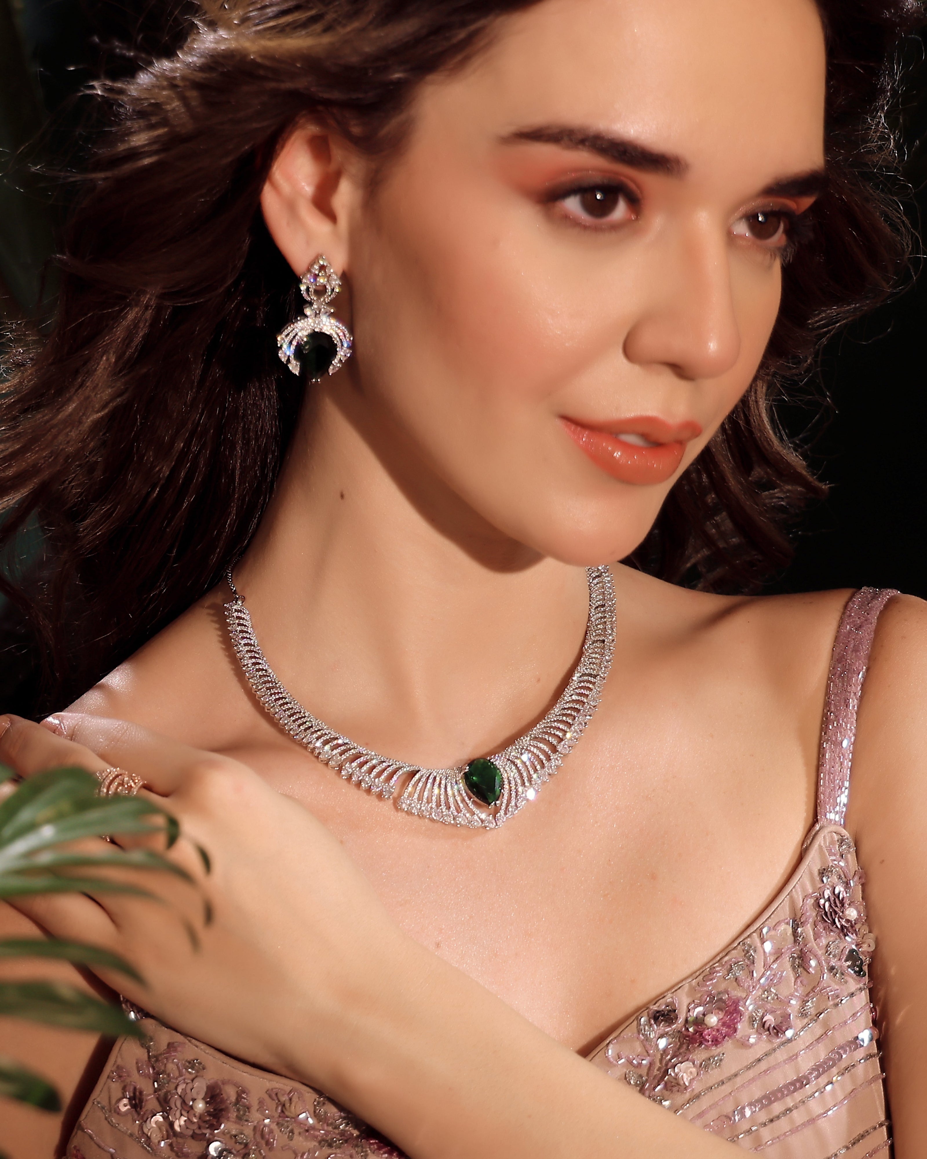 Woman wearing a silver necklace and earrings with a dark background
