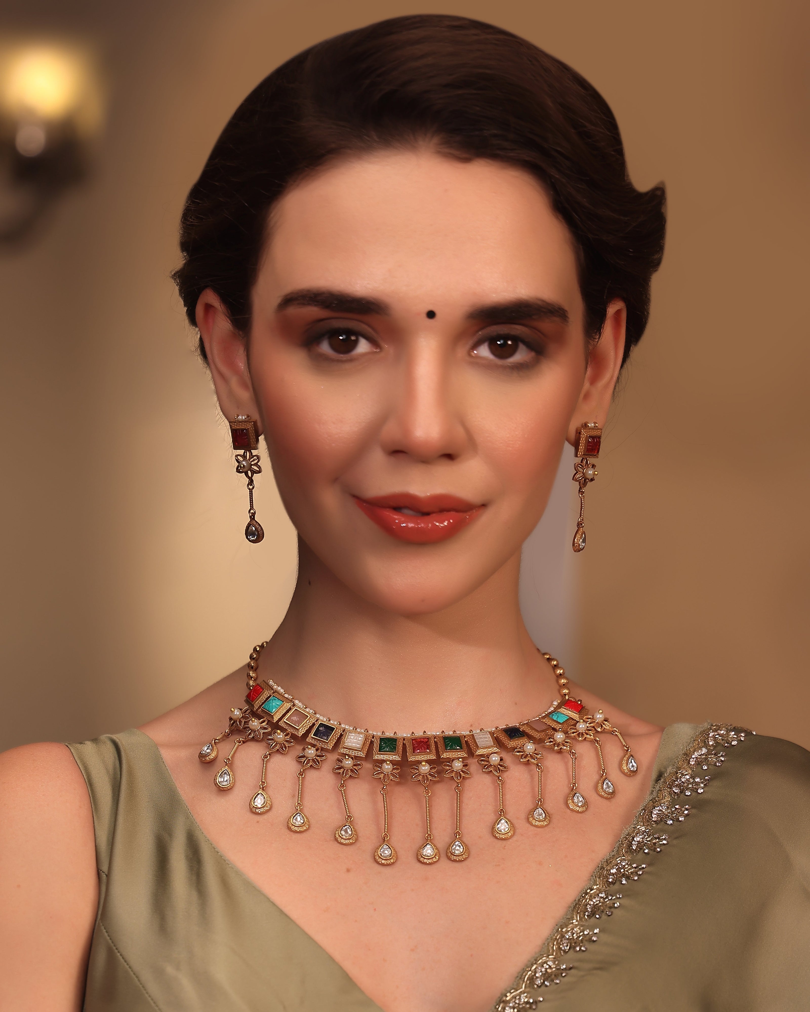Woman wearing a decorative necklace and earrings with a plain background