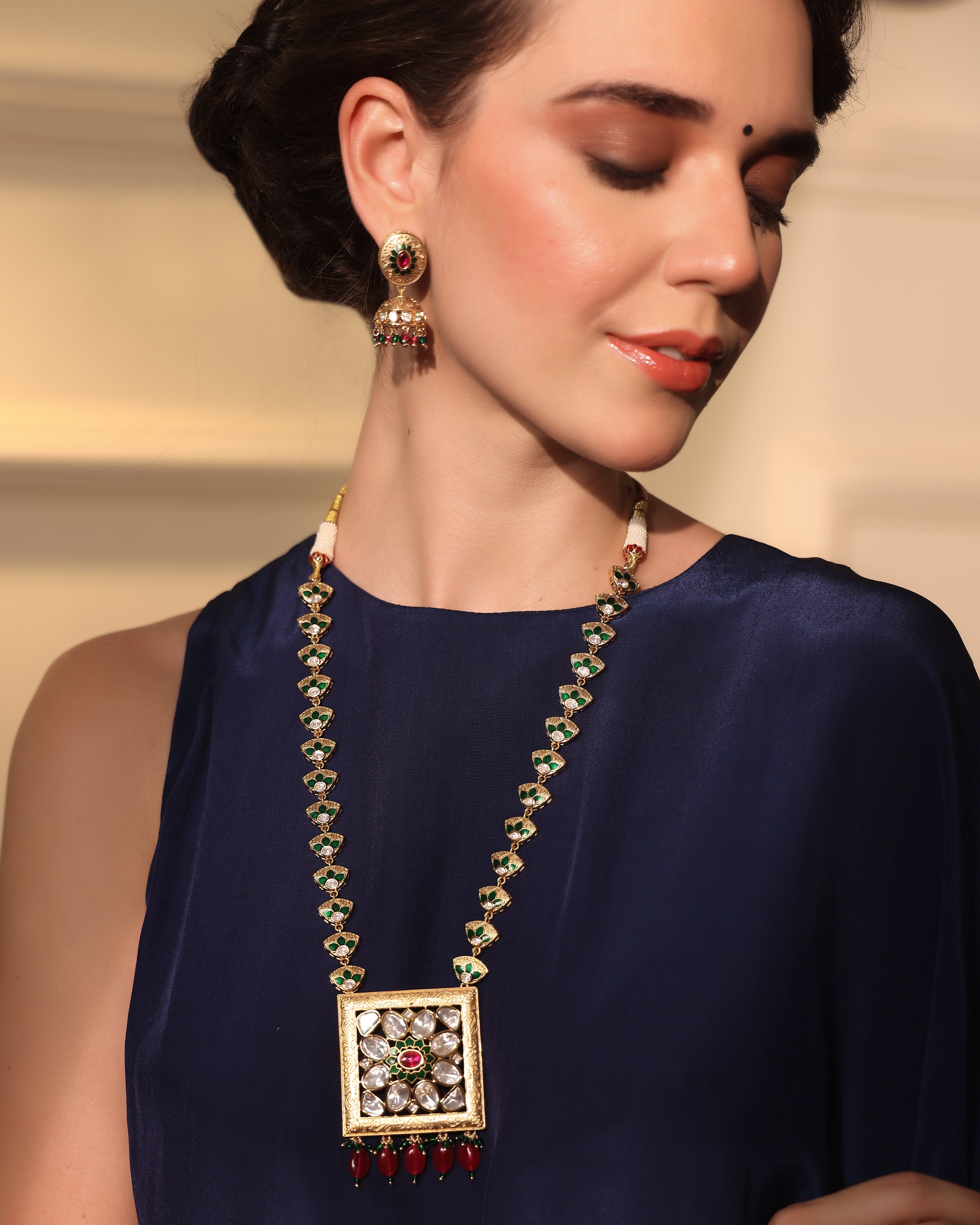 Woman wearing a necklace and earrings with a neutral background