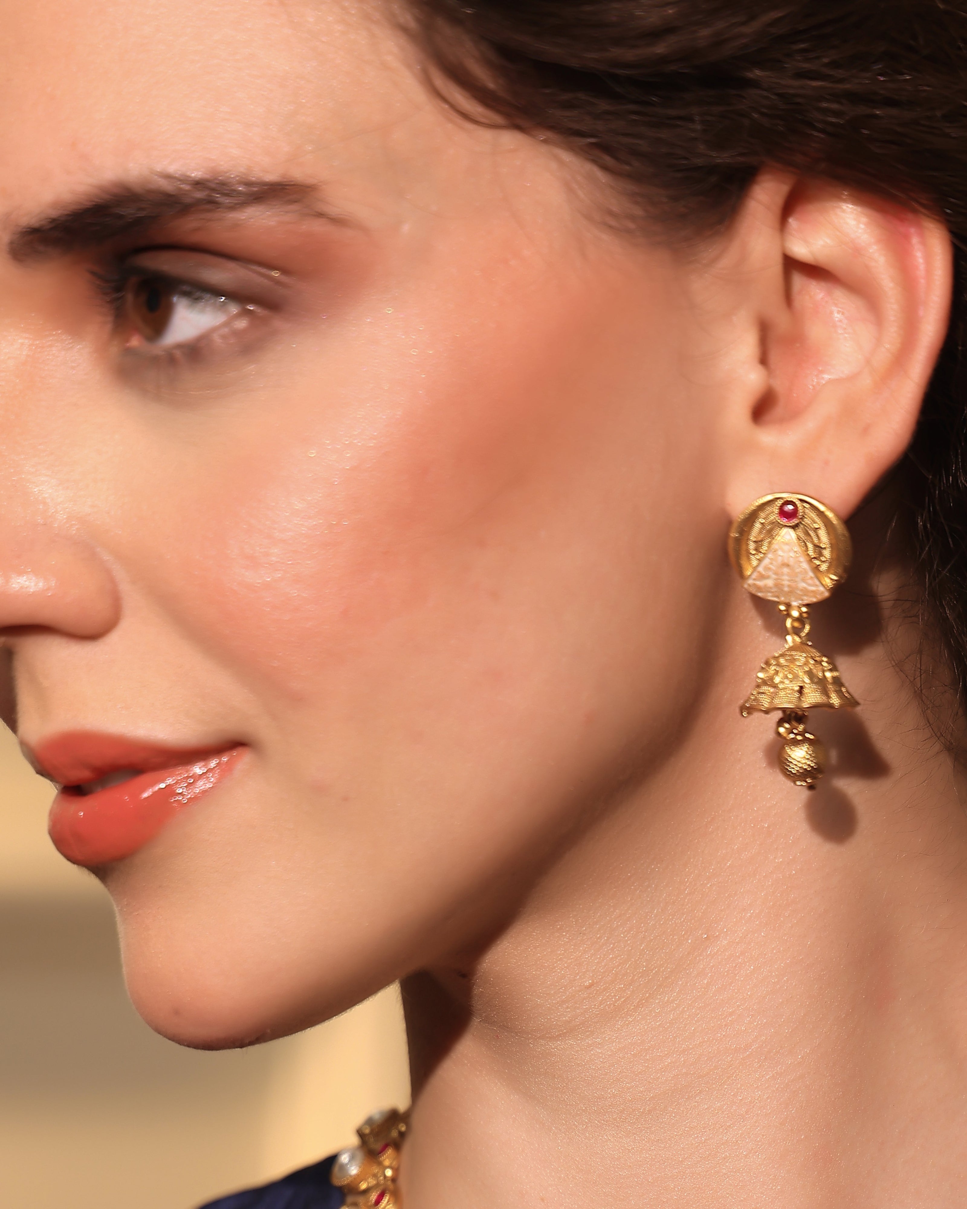 Close-up of a woman wearing gold earrings with a blurred background