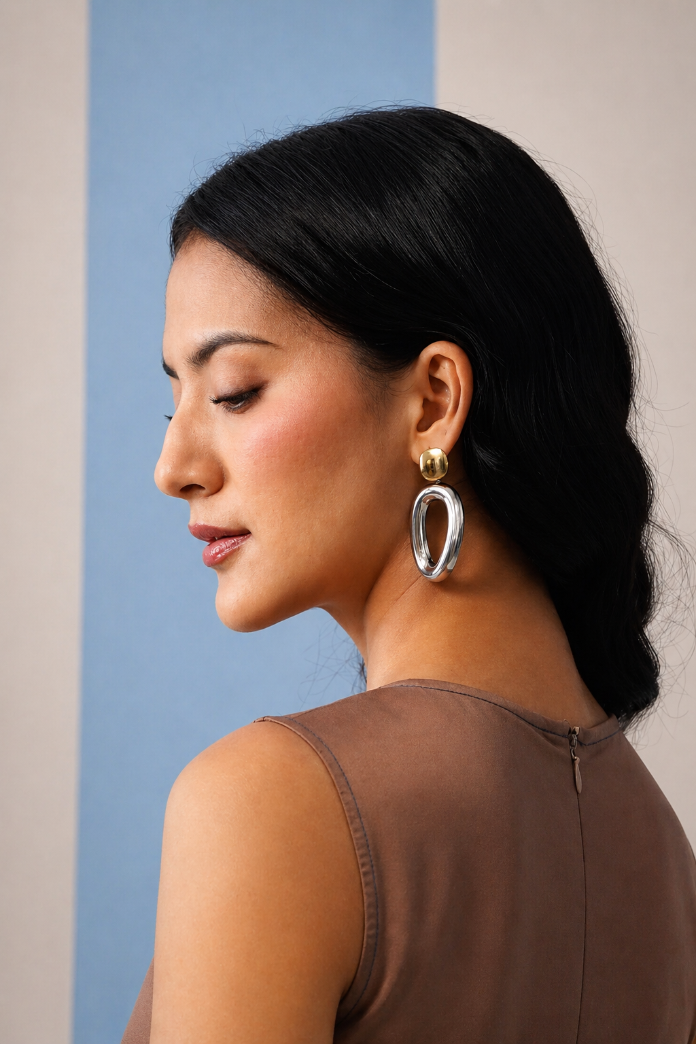 Woman wearing large hoop earrings with a neutral background
