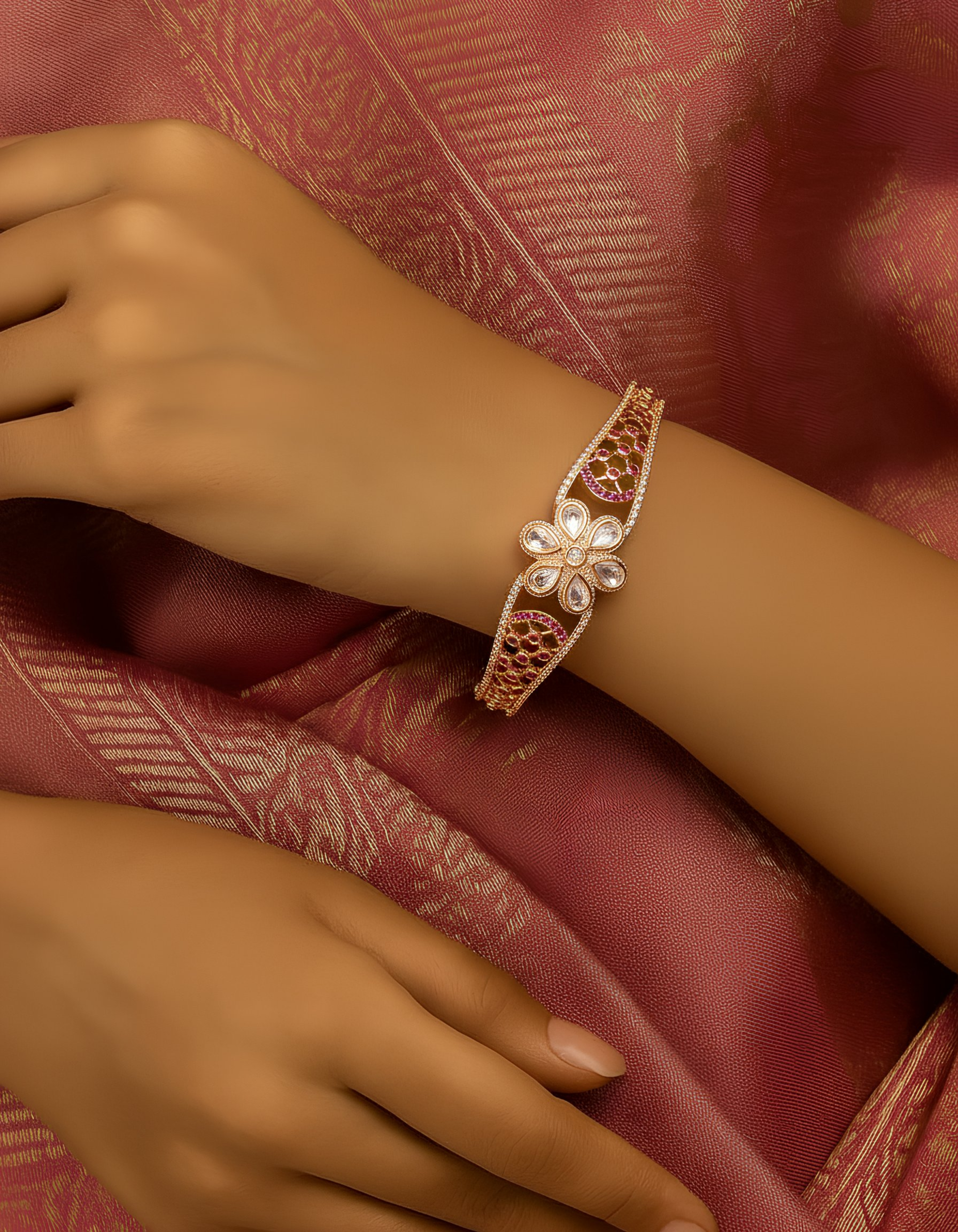 Close-up of a hand wearing a decorative bracelet on a pink fabric background