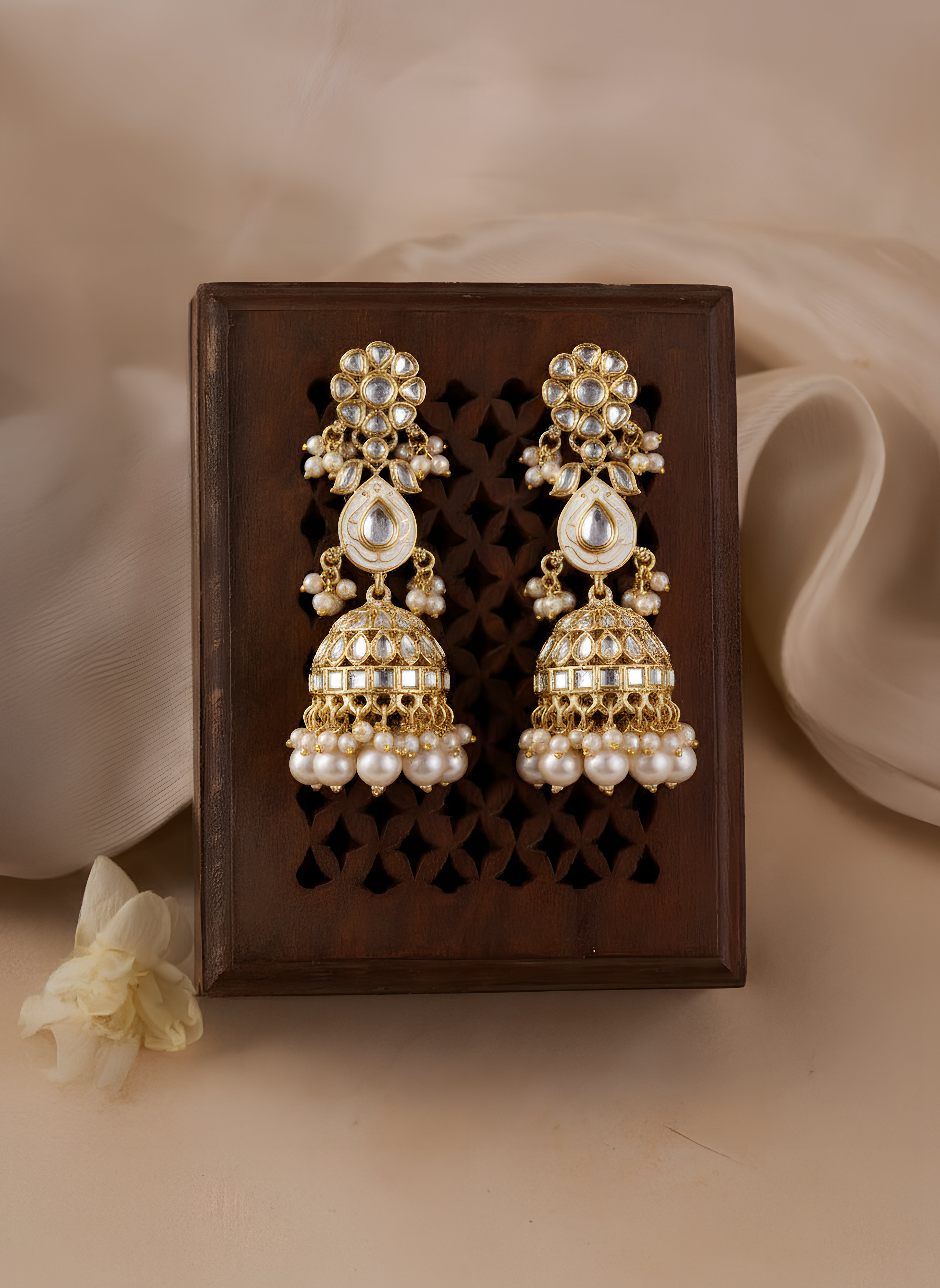 Pair of gold and pearl earrings on a decorative box with a beige background