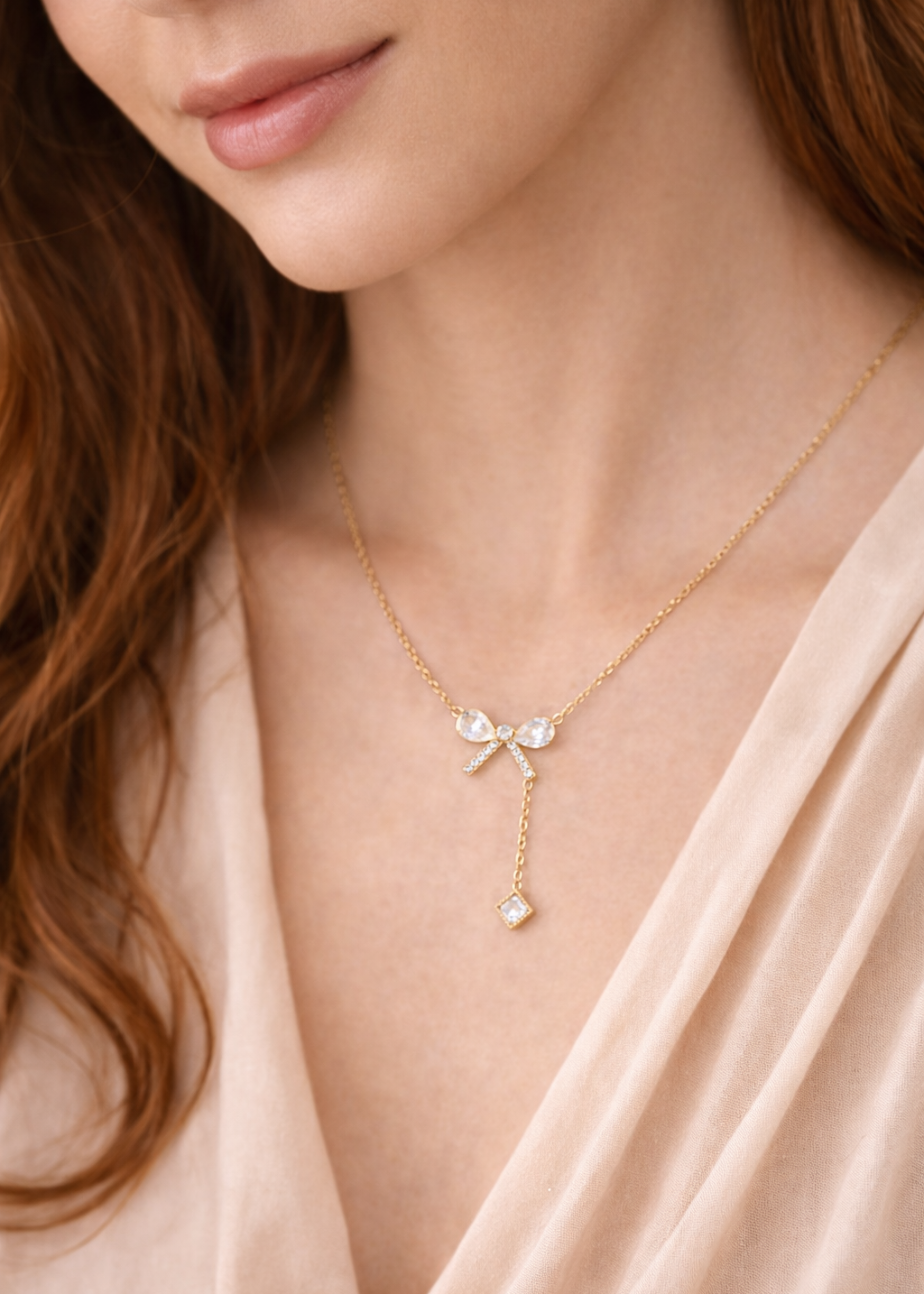 Close-up of a woman wearing a delicate gold necklace with a bow and heart pendant.