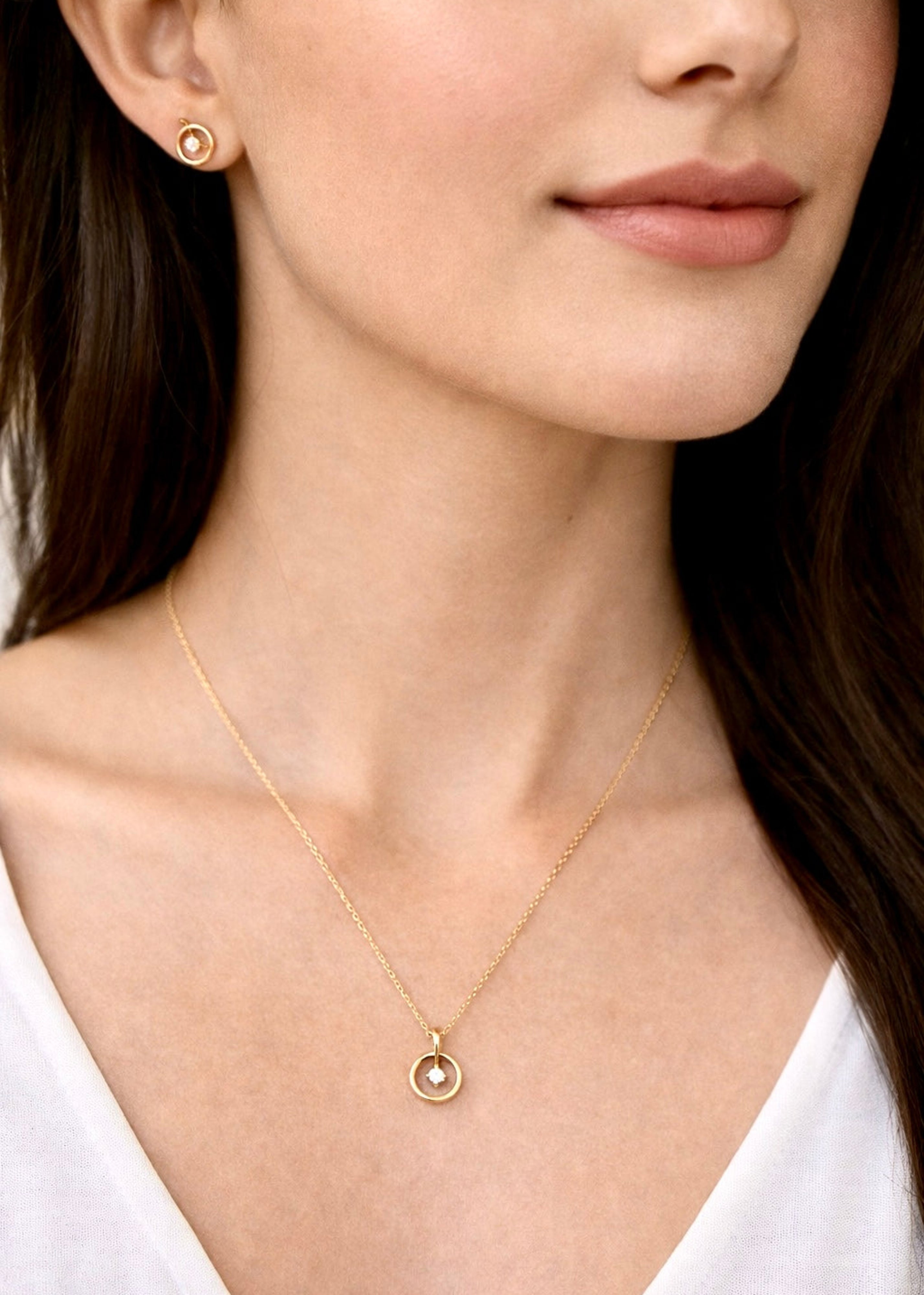 Close-up of a woman wearing a gold necklace and earrings.