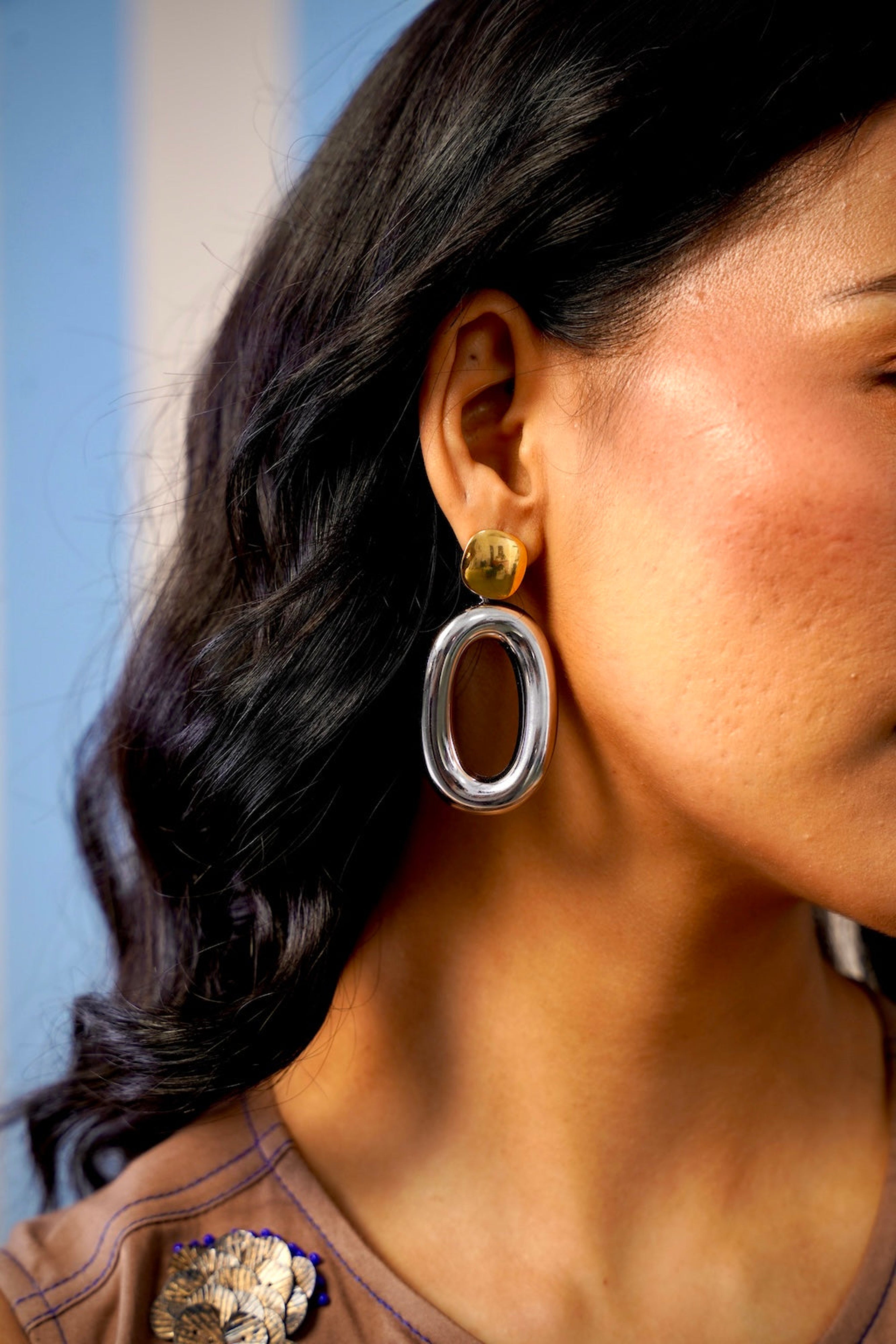 Close-up of a person wearing silver hoop earrings with a blurred background