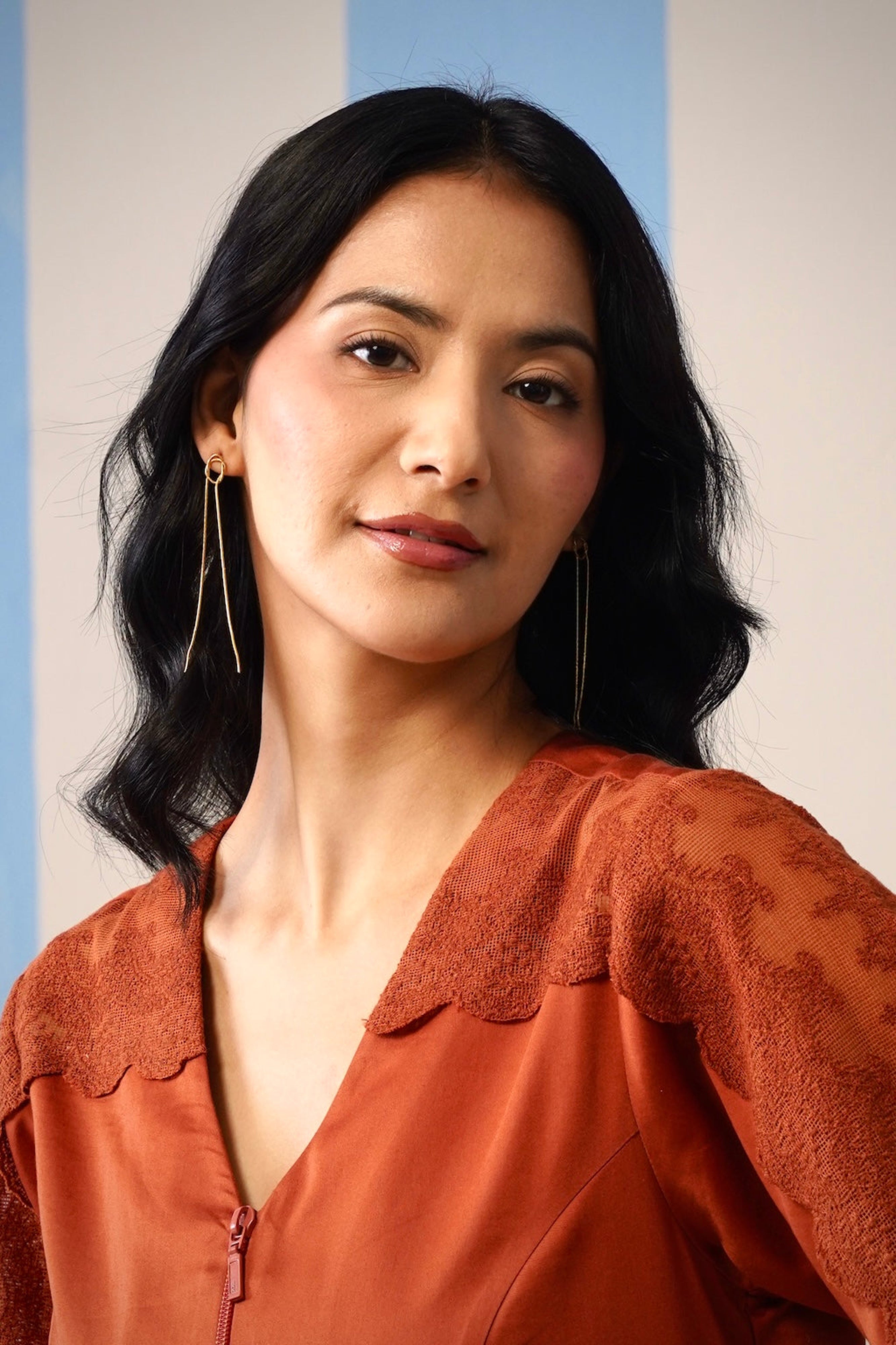 Woman wearing a rust-colored blouse with a plain background