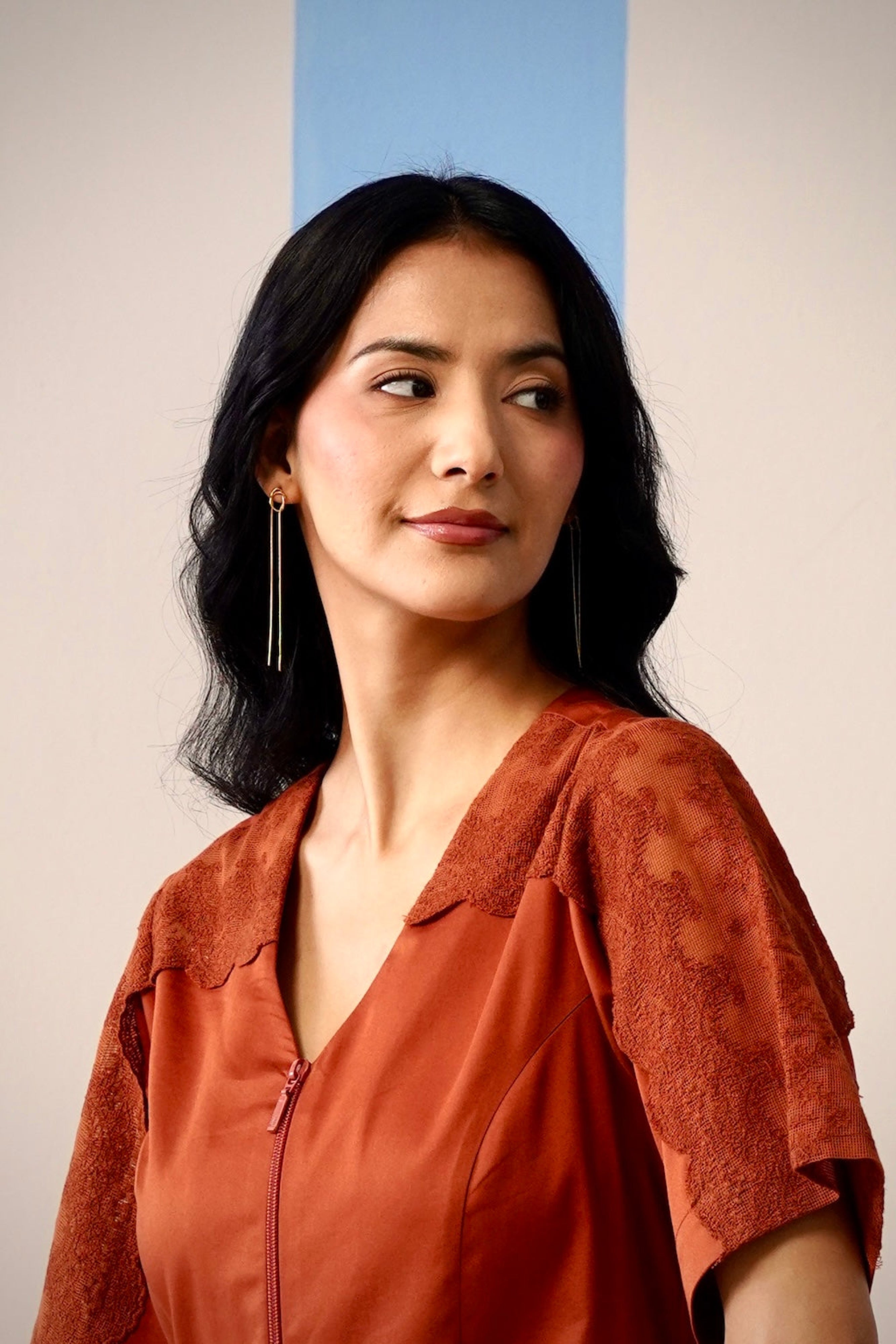 Woman wearing a rust-colored blouse against a plain background