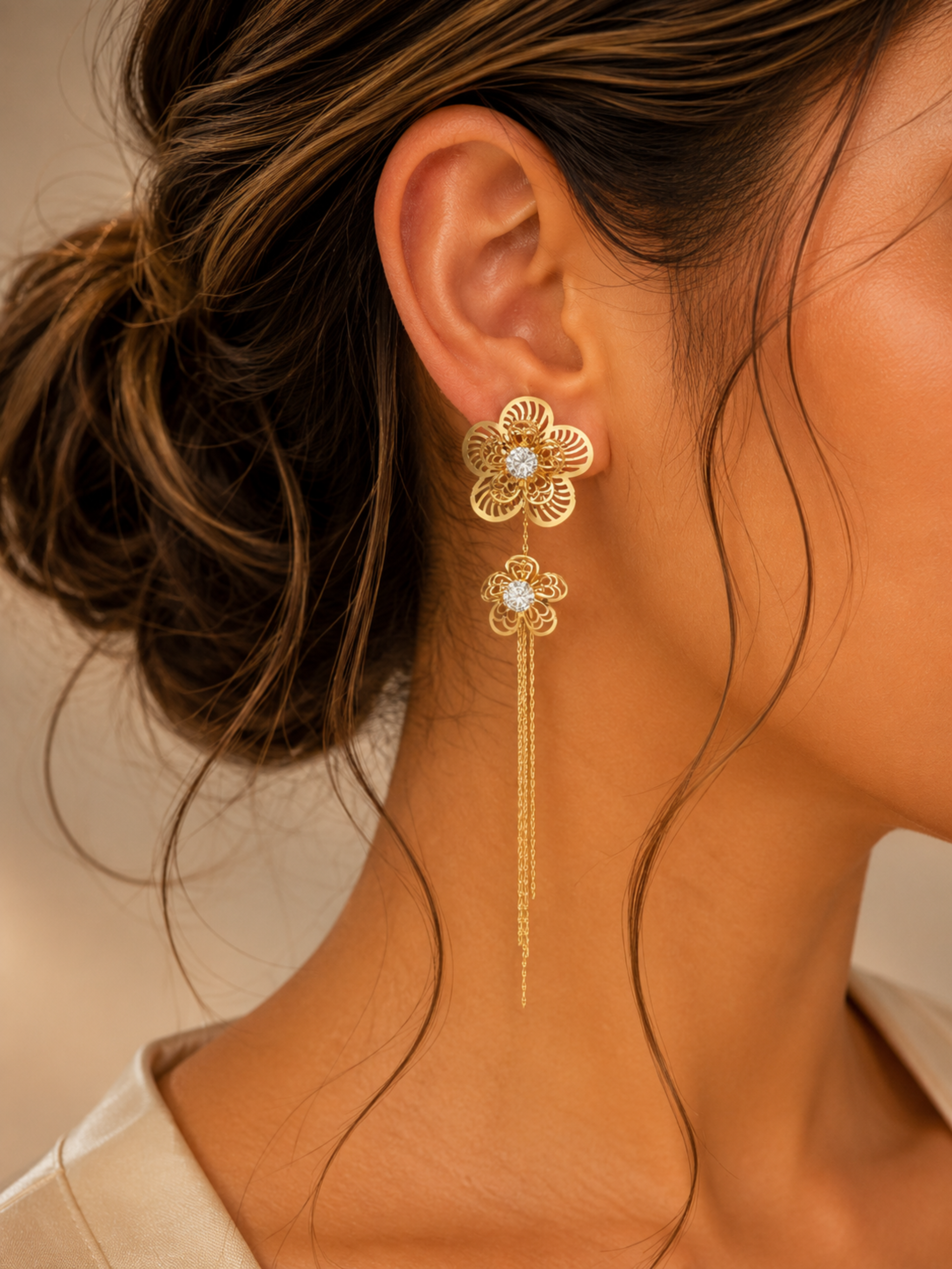 Gold floral earring worn by a person with a neutral background