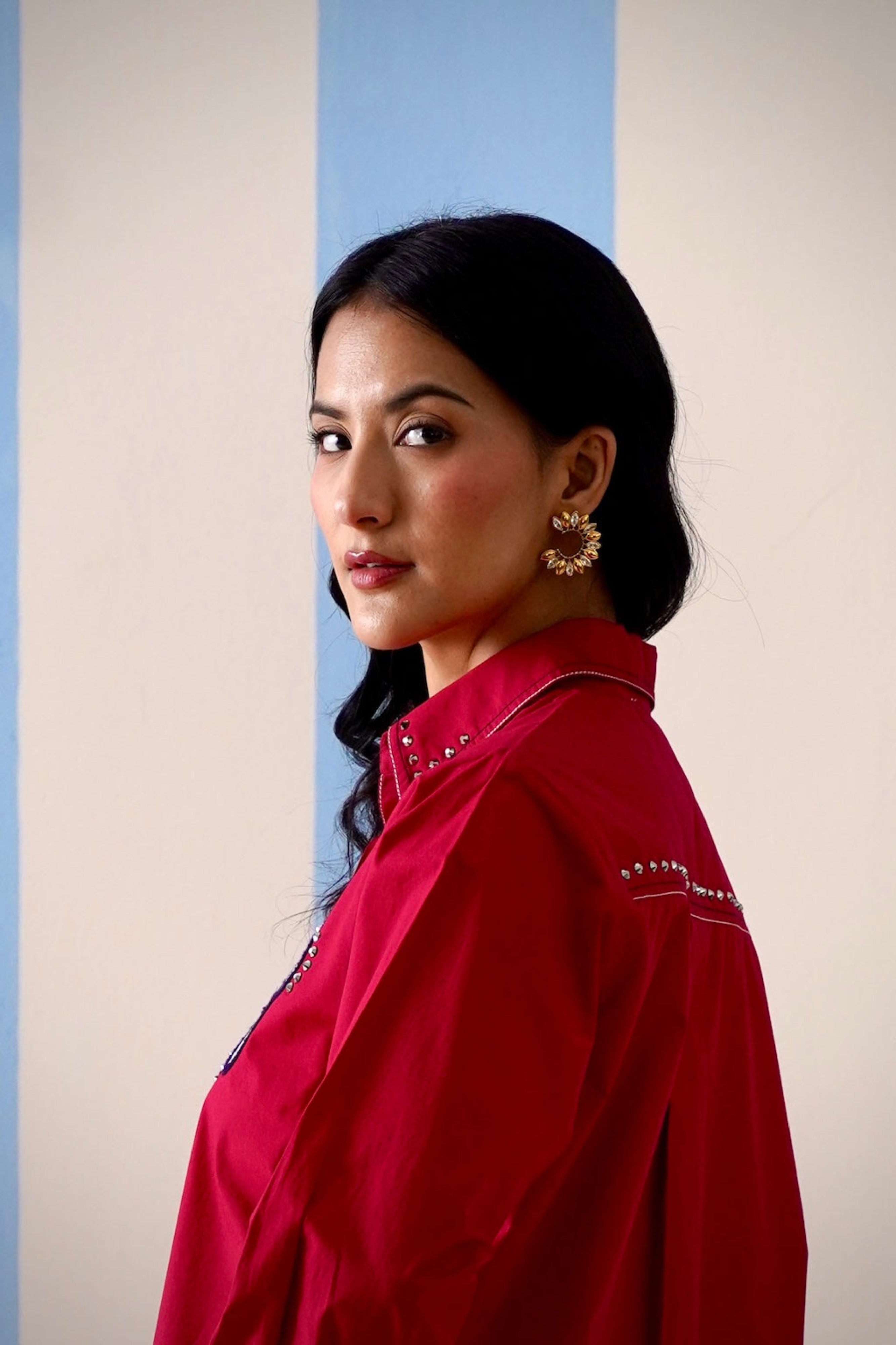 Woman wearing a red blouse with decorative elements against a light background