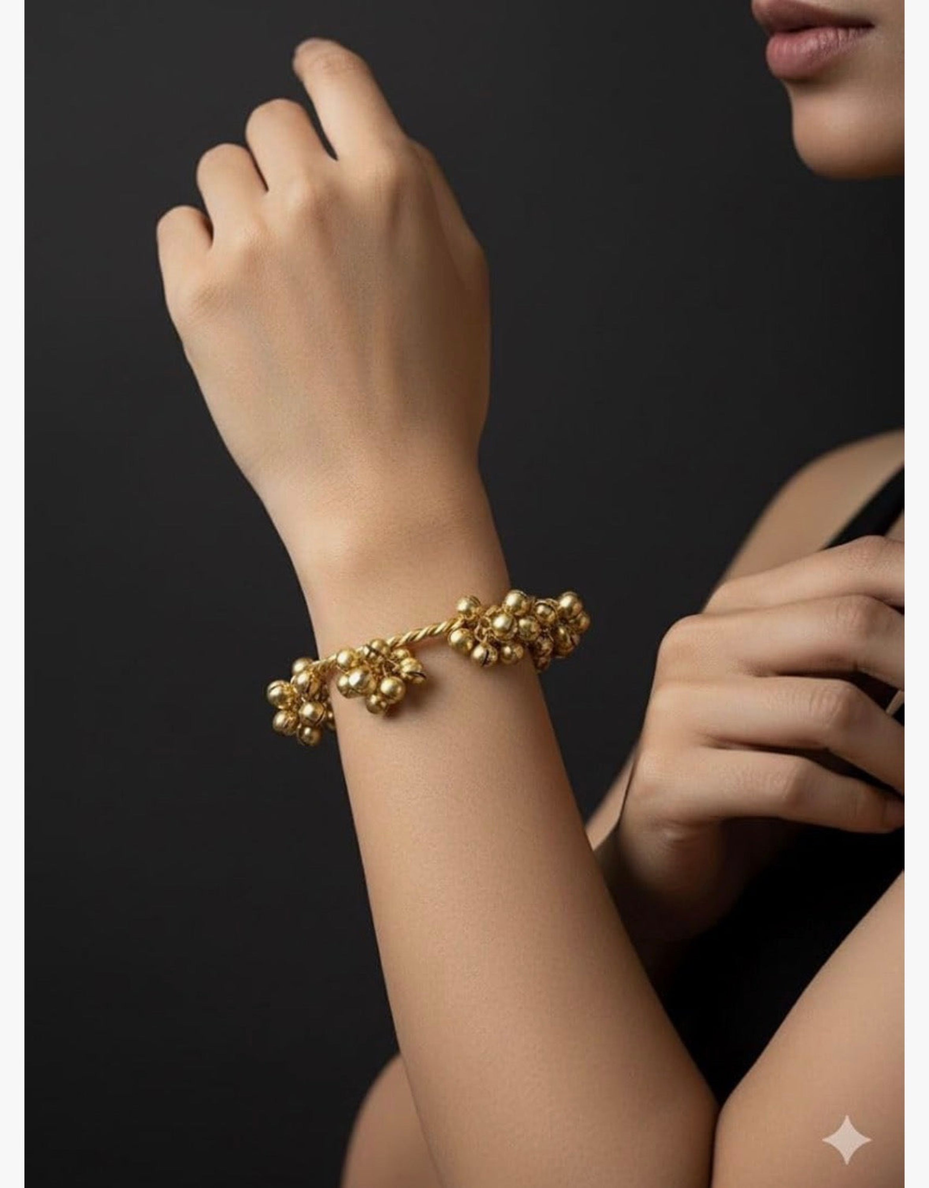 Gold bracelet on a person's wrist against a dark background