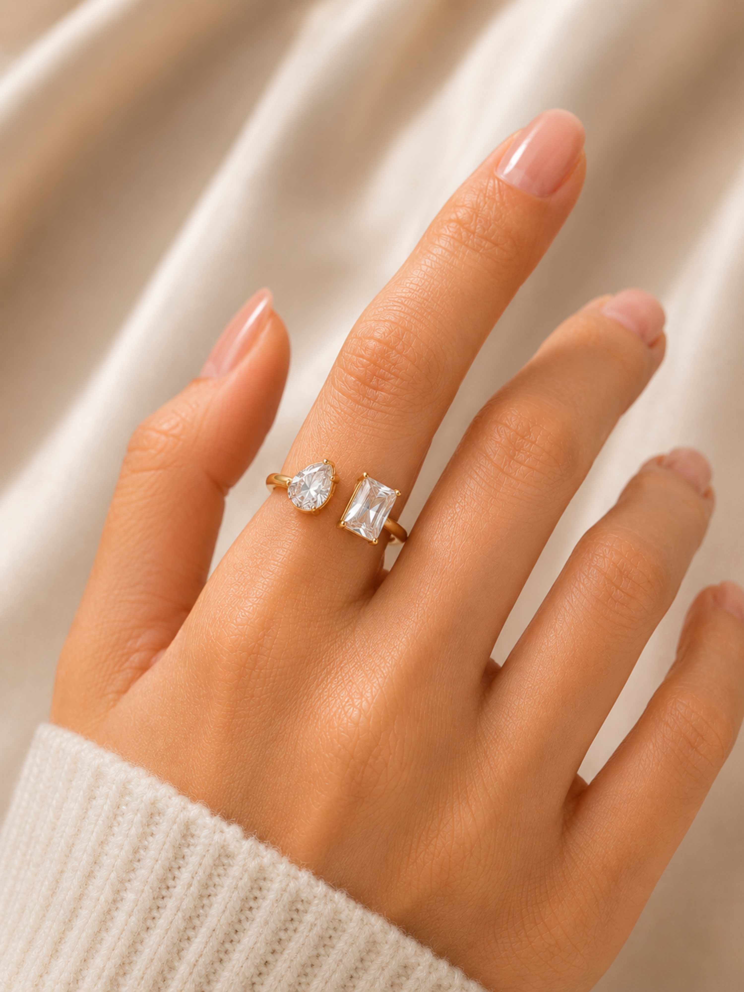 Hand wearing a gold ring with a diamond on a neutral background
